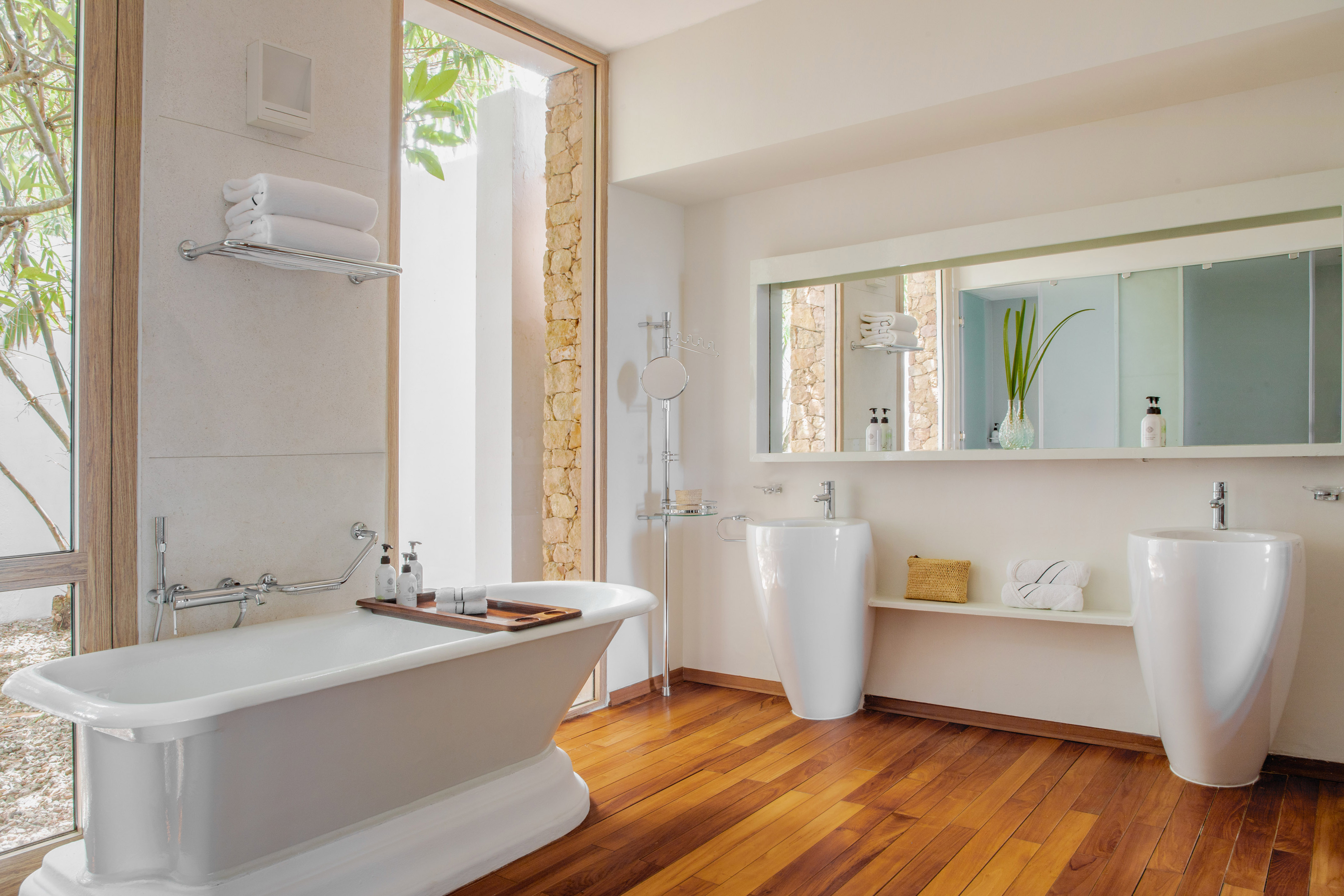 Bright luxury bathroom with freestanding tub, dual sinks, and wood floor.