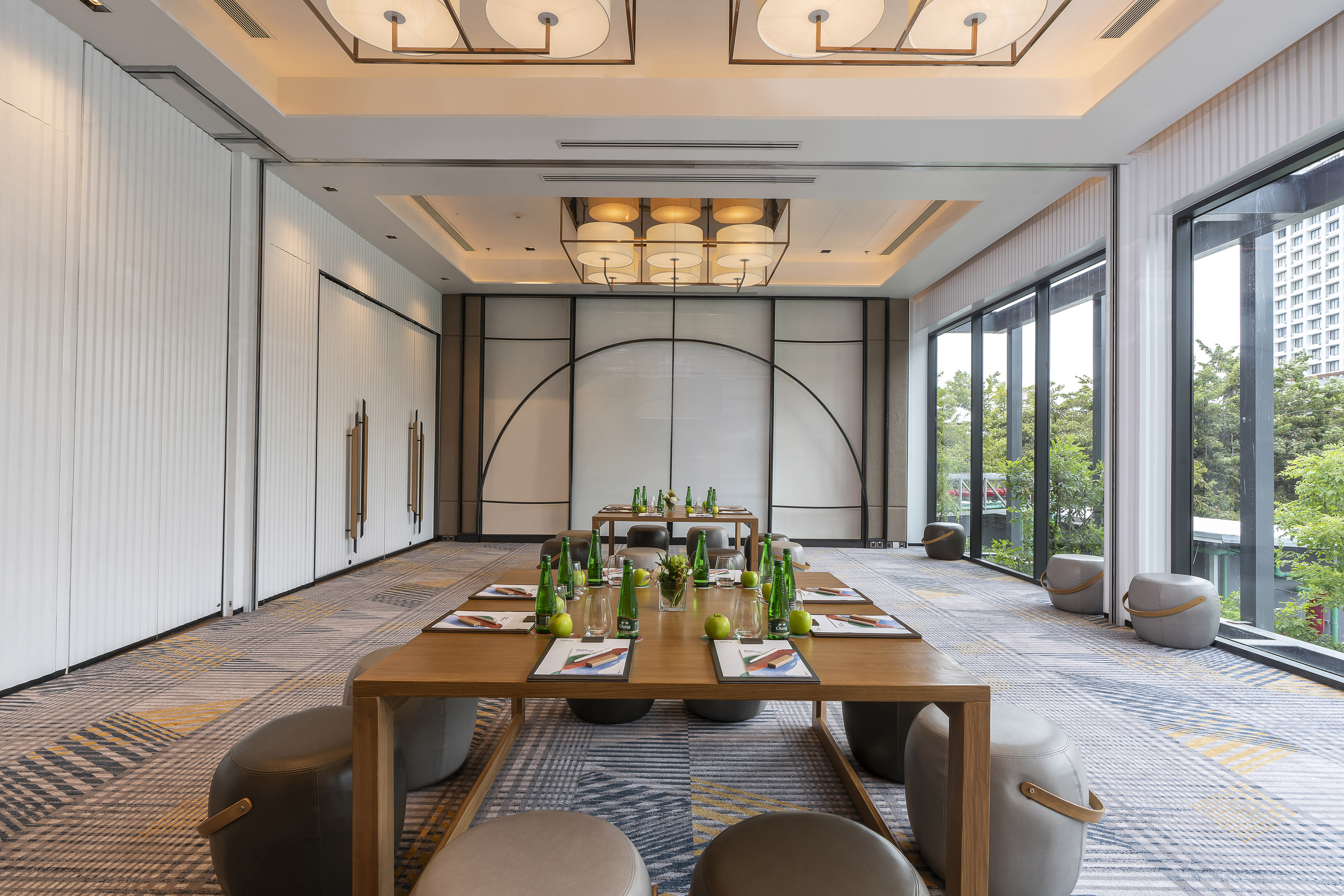 Contemporary meeting room with tables, poufs, and large windows for events.
