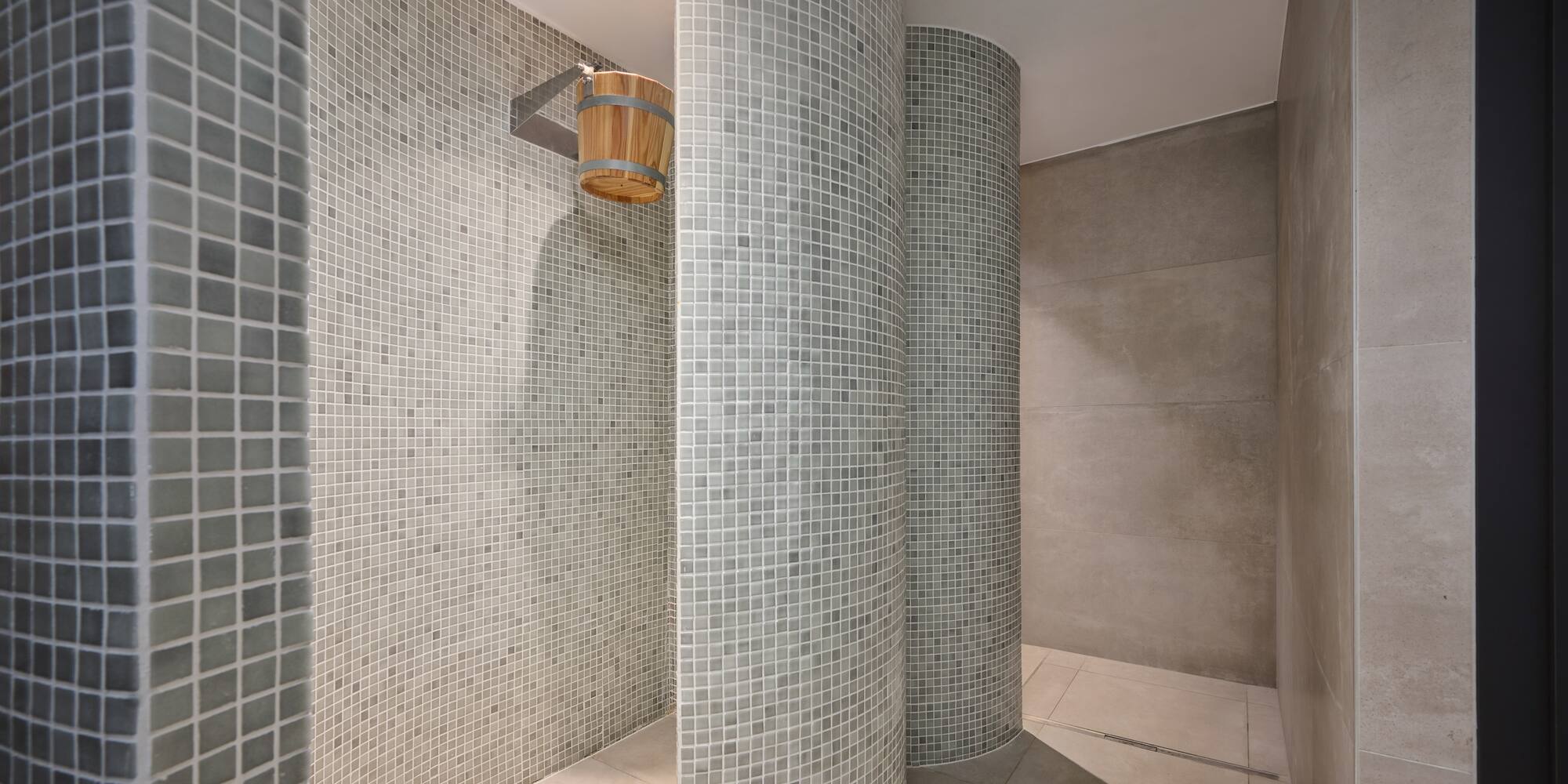 a shower with a bucket and a tile wall