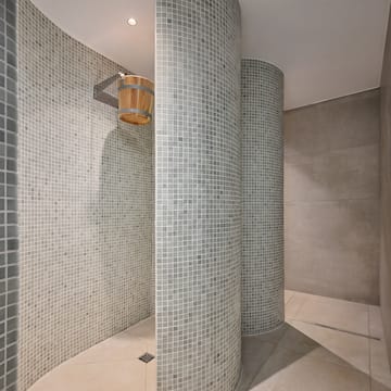 a shower with a bucket and a tile wall