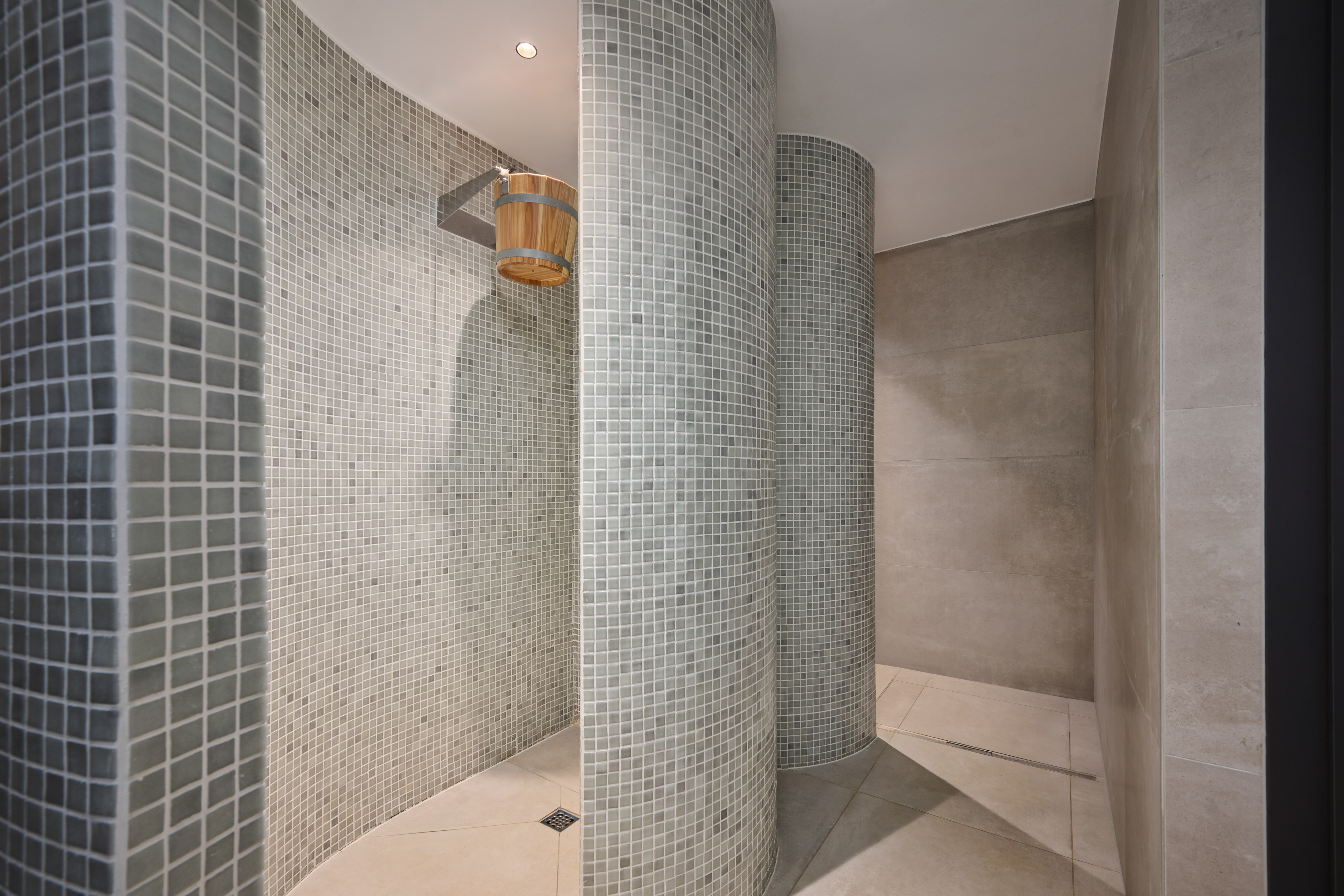 a shower with a bucket and a tile wall