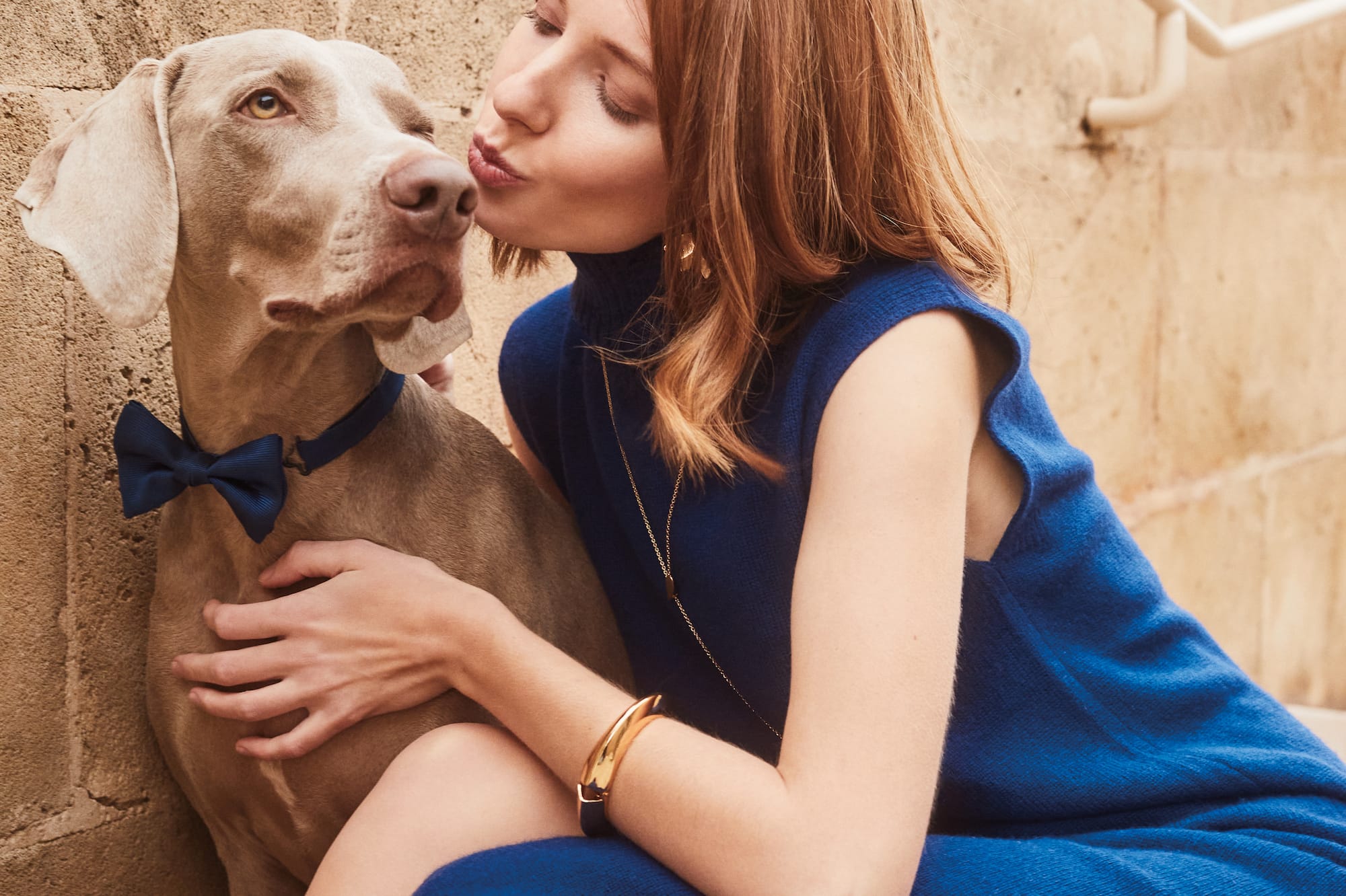 a woman in a blue dress kissing a dog