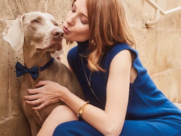 a woman in a blue dress kissing a dog