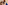 Red-haired woman in blue dress kissing Weimaraner dog wearing blue bow tie.