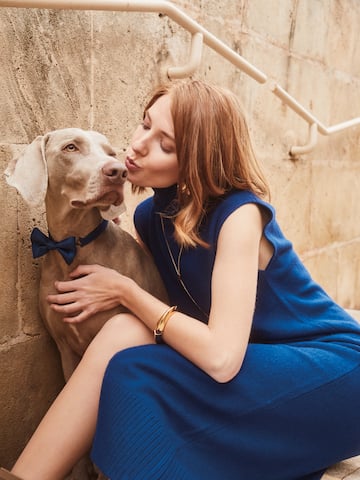 a woman in a blue dress kissing a dog