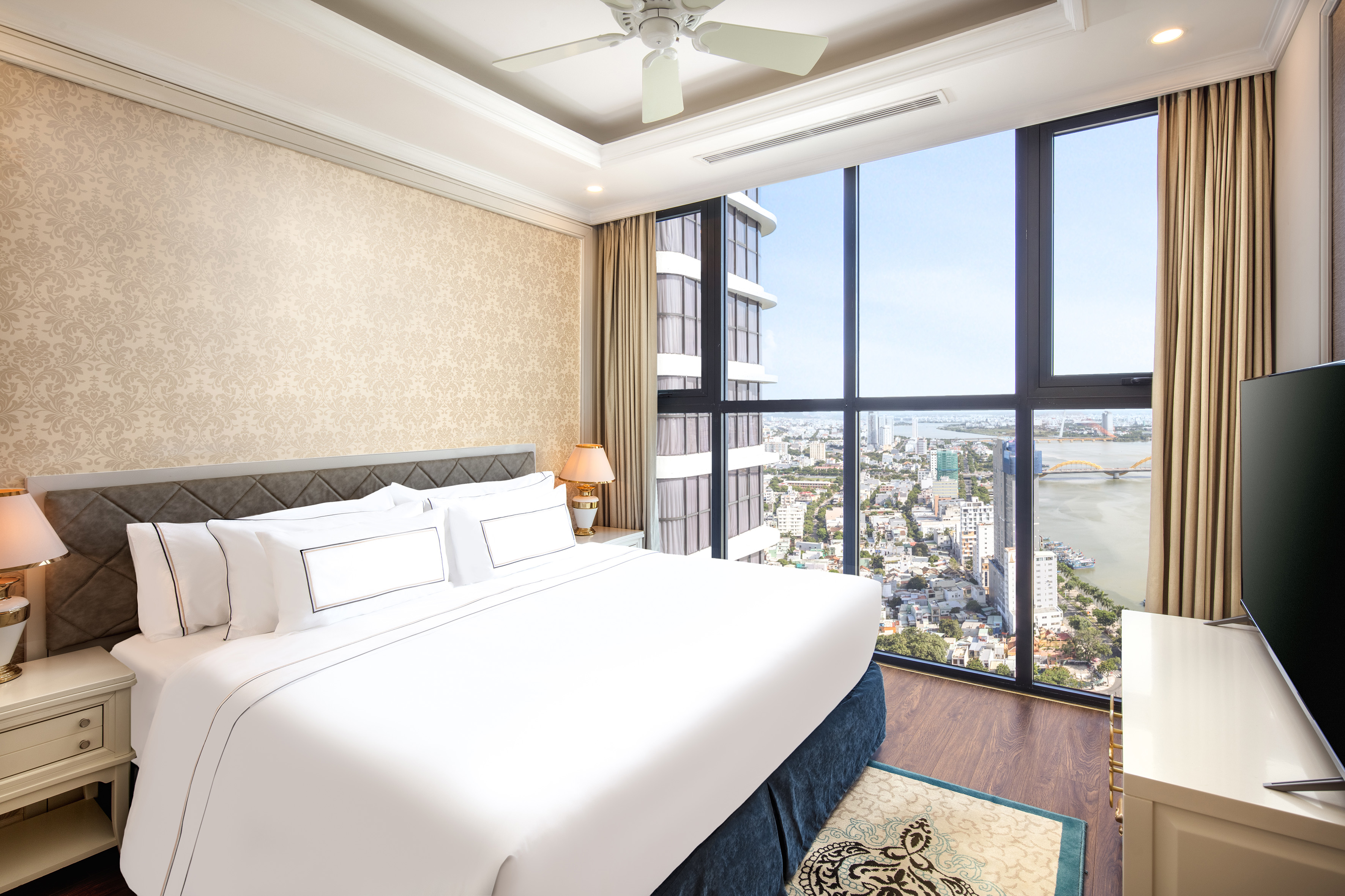 Modern hotel bedroom with king bed and panoramic city river view.
