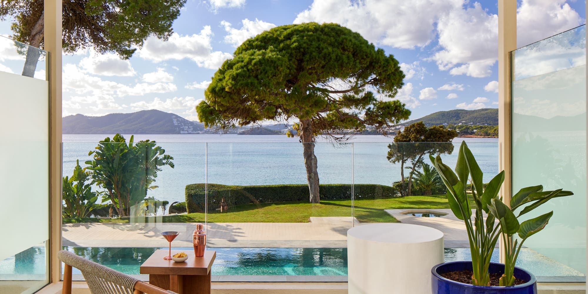 a pool with a table and chairs and a table with a tree and water in the background