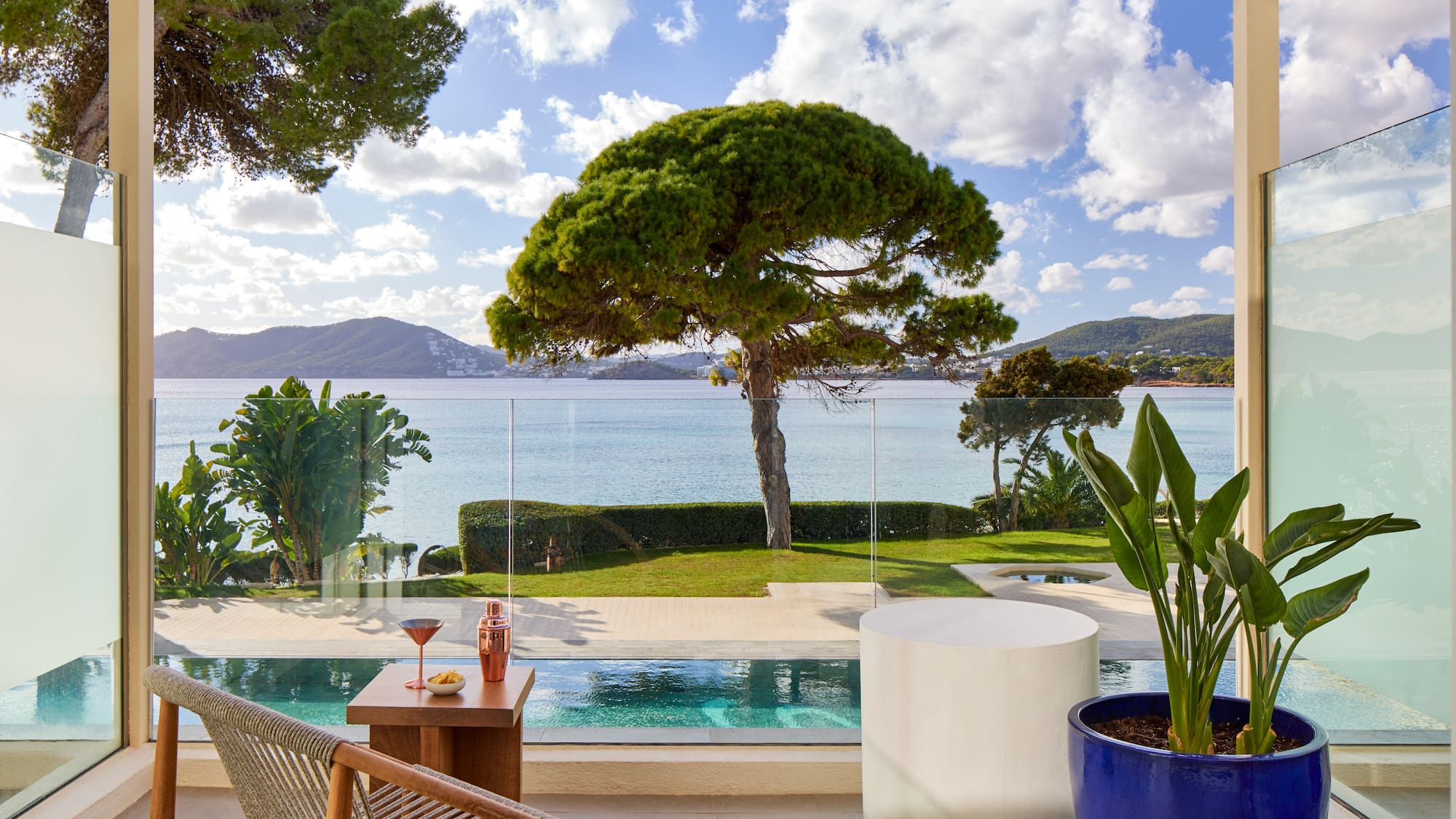 a pool with a table and chairs and a table with a tree and water in the background
