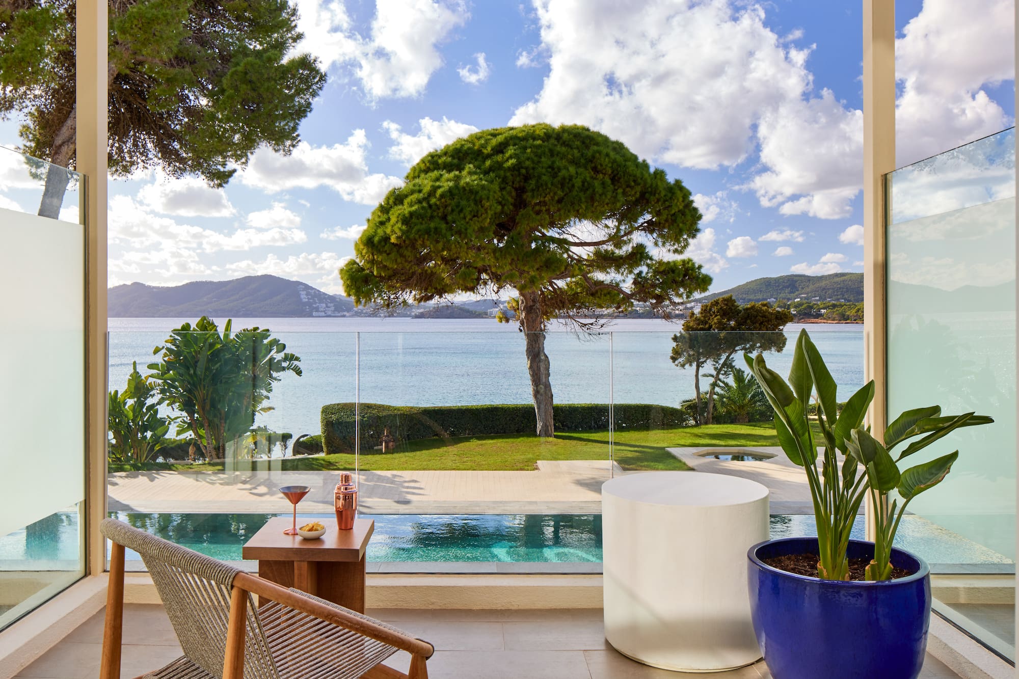 a pool with a table and chairs and a table with a tree and water in the background