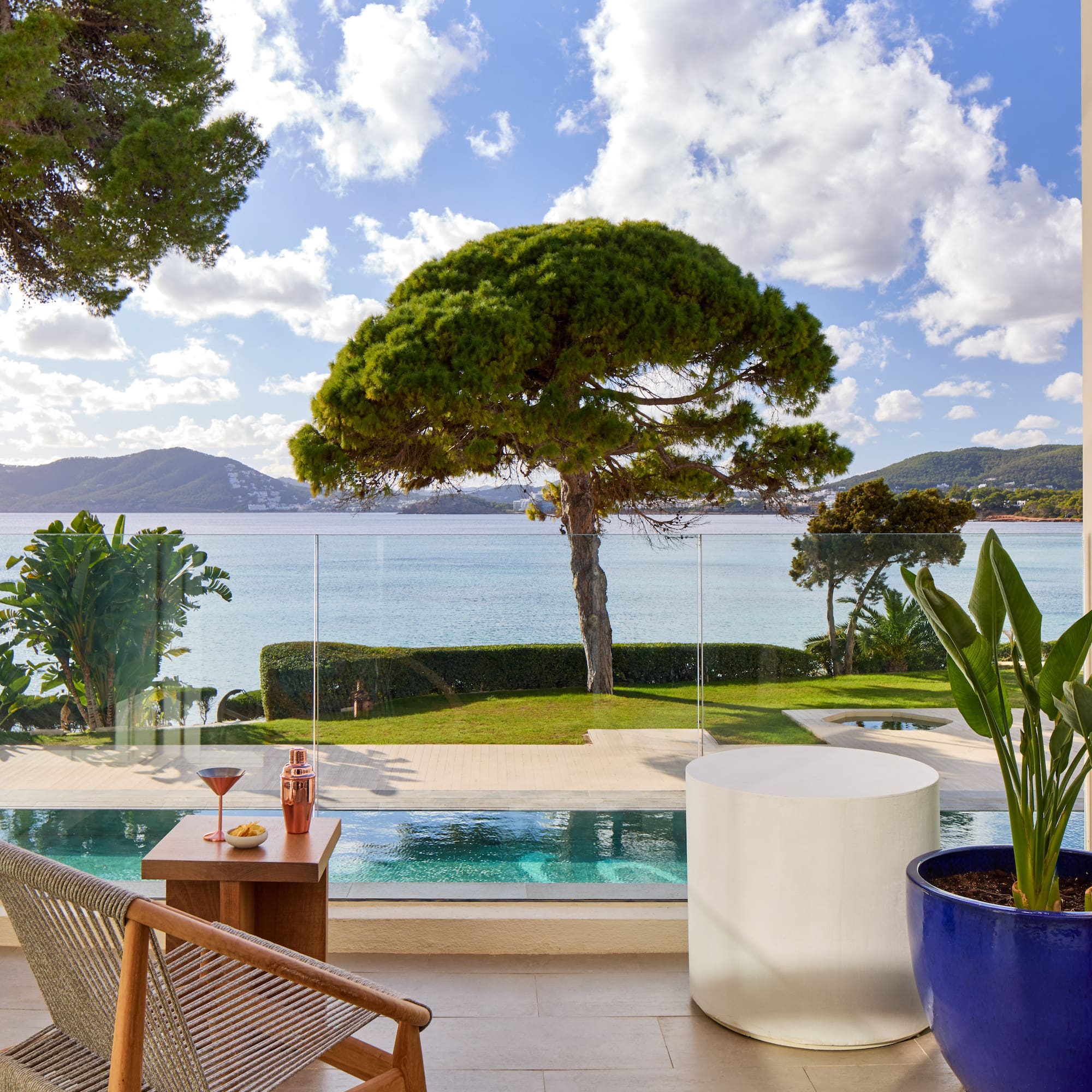 a pool with a table and chairs and a table with a tree and water in the background