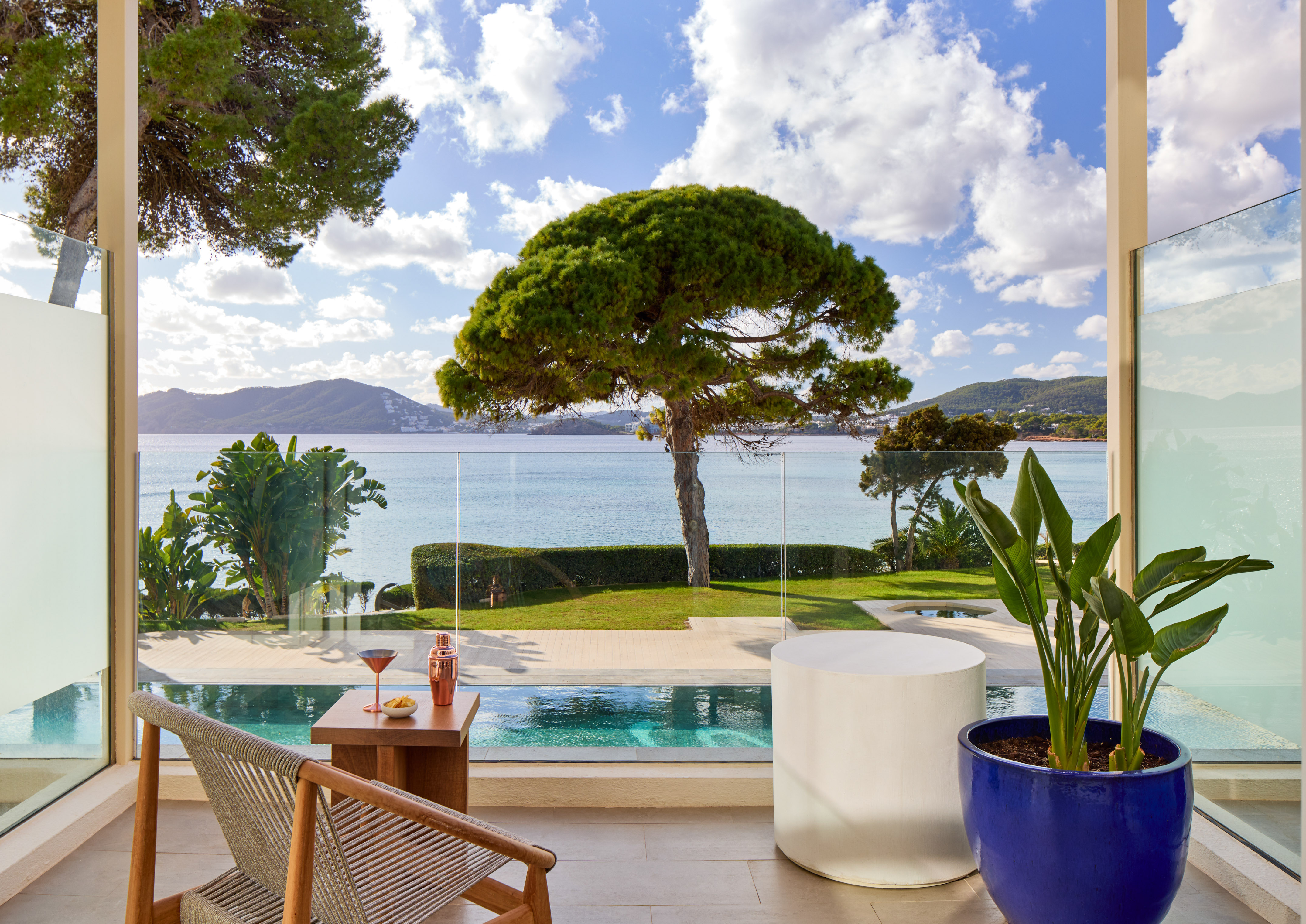 a pool with a table and chairs and a table with a tree and water in the background