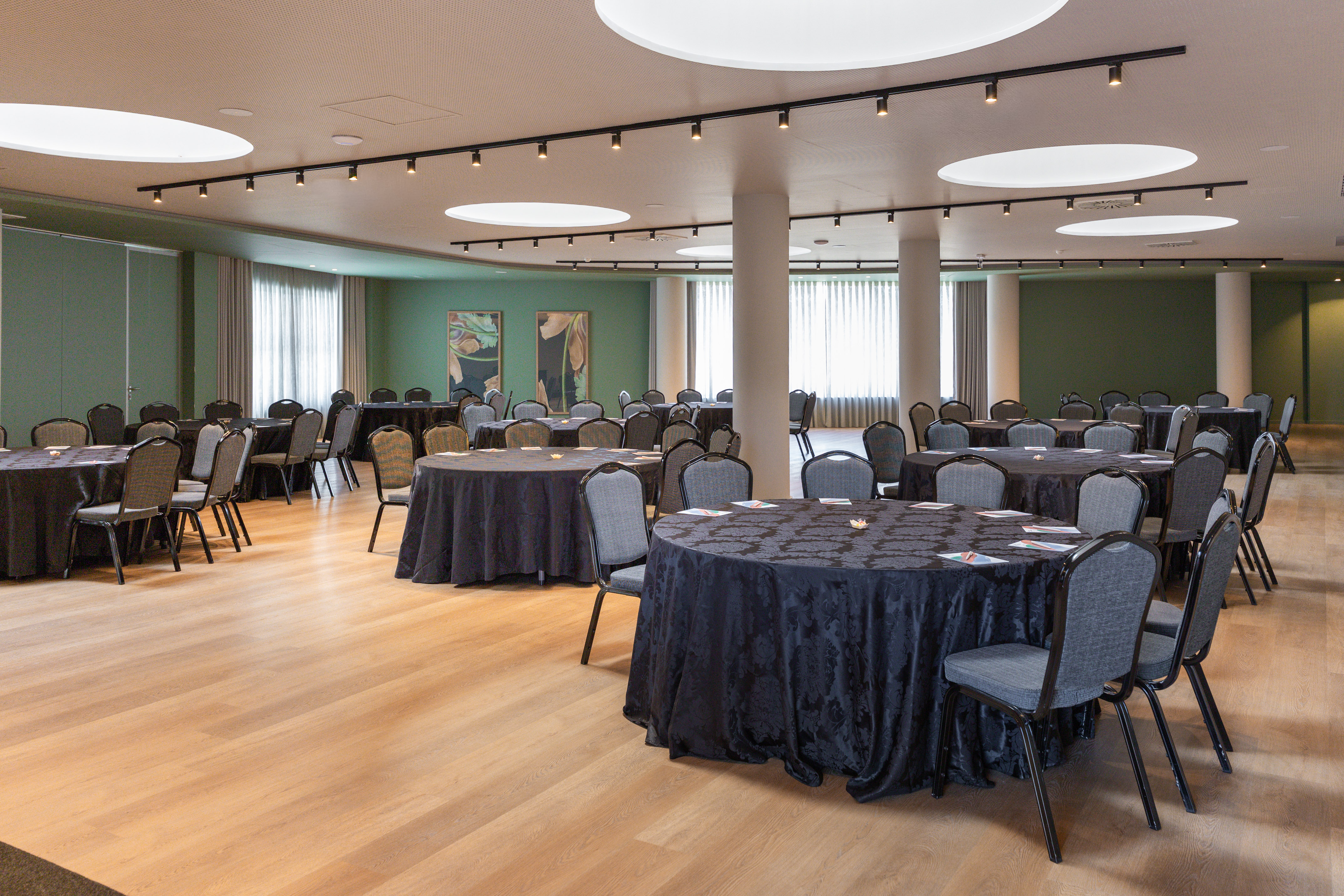 Hotel meeting room with round banquet tables, dark linens, grey chairs.