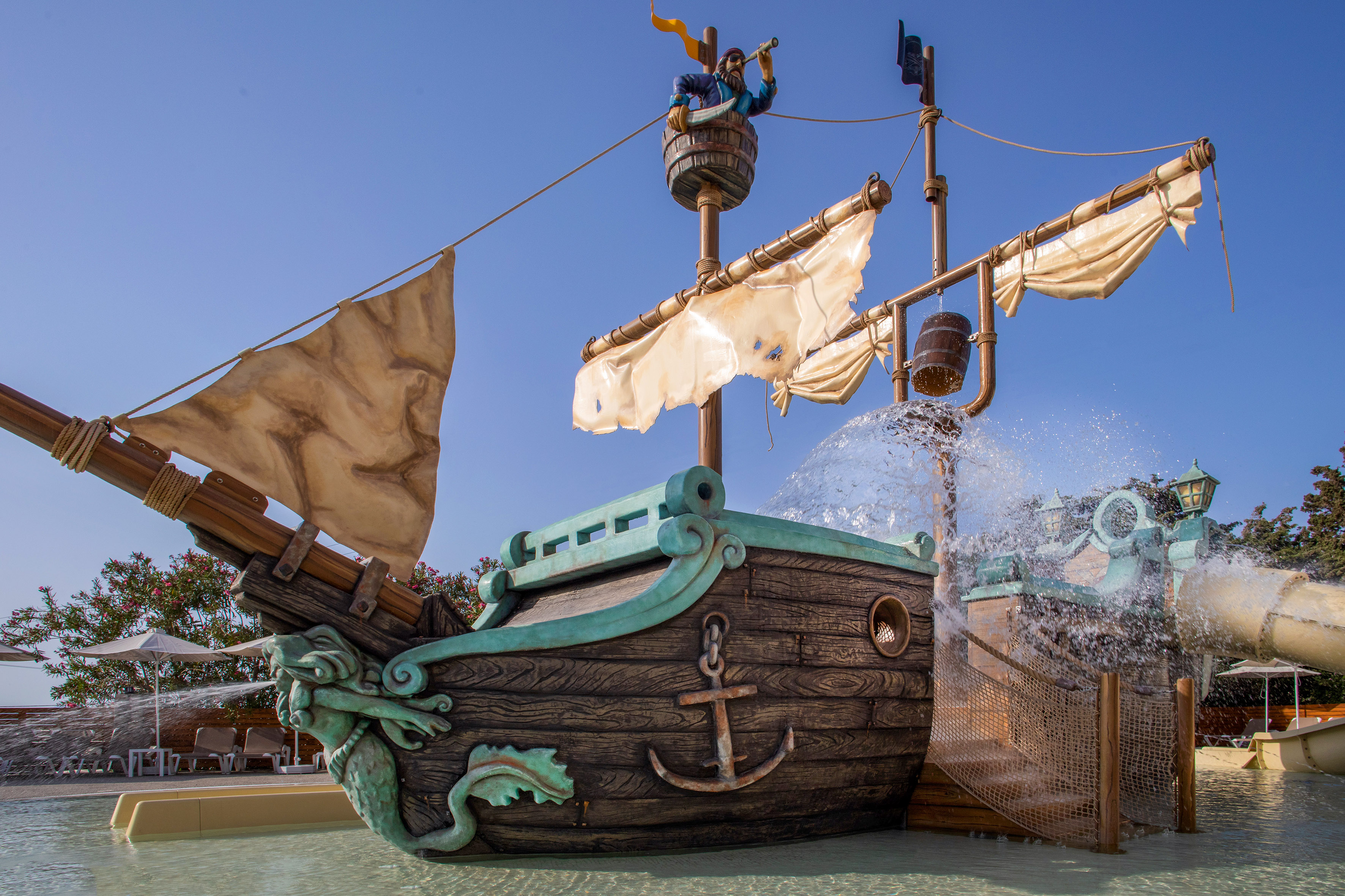 Pirate ship water park with pirate figure, splashing water, and slides.