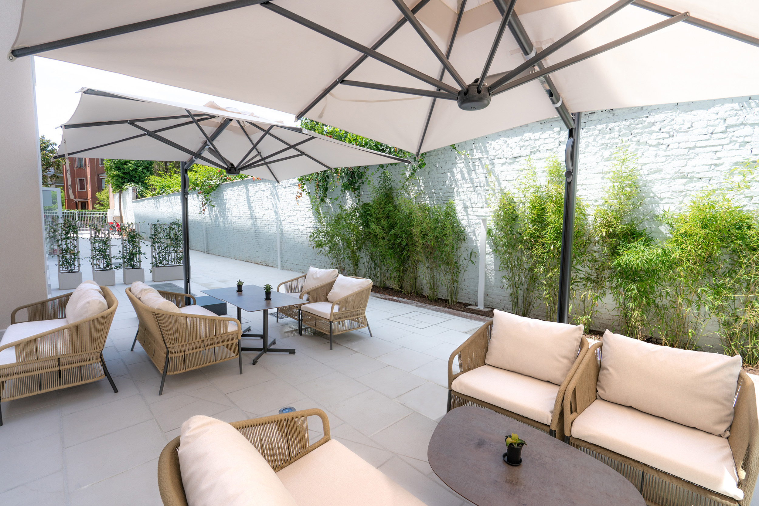 a patio with chairs and tables under a white umbrella