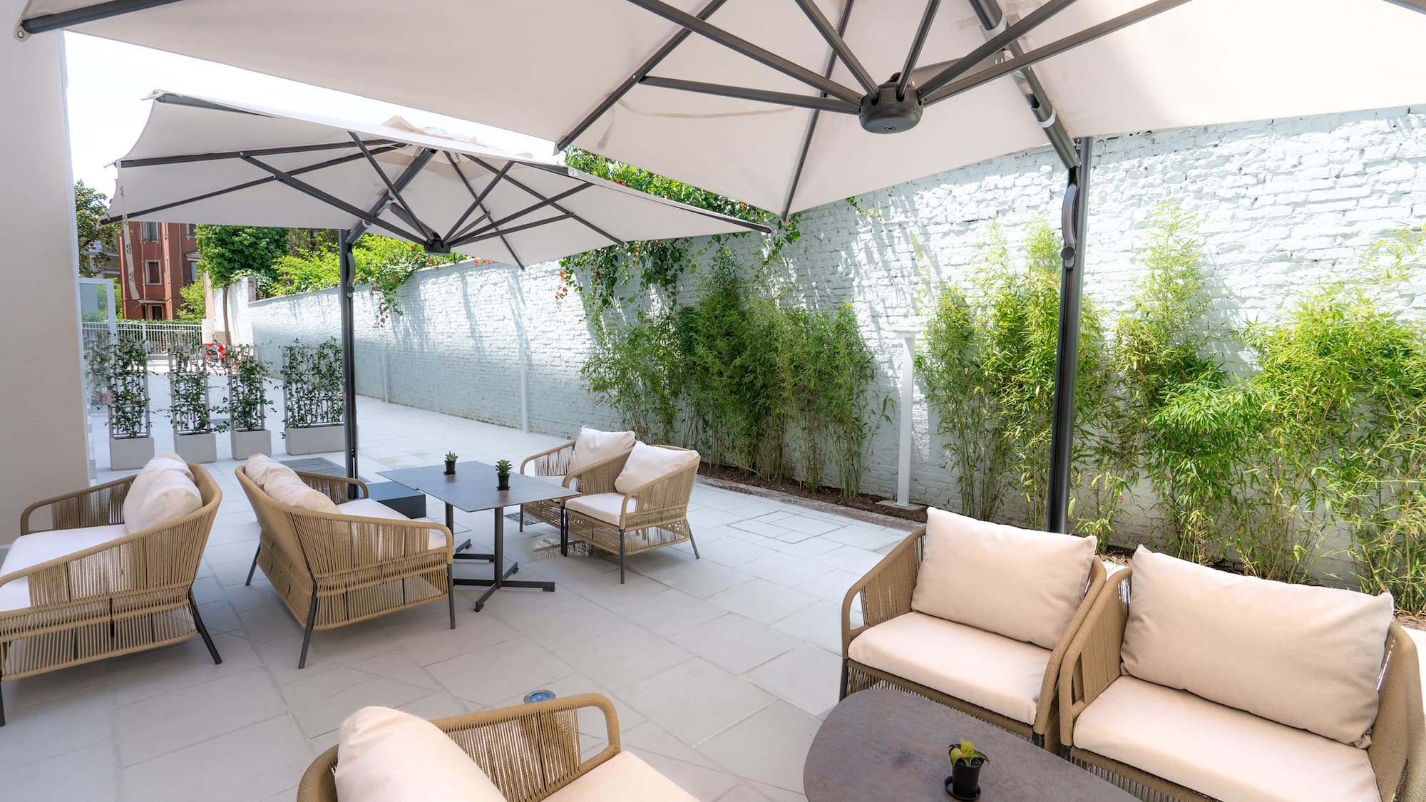 a patio with chairs and tables under a white umbrella