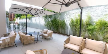 a patio with chairs and tables under a white umbrella