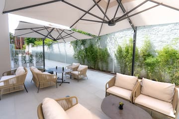 a patio with chairs and tables under a white umbrella