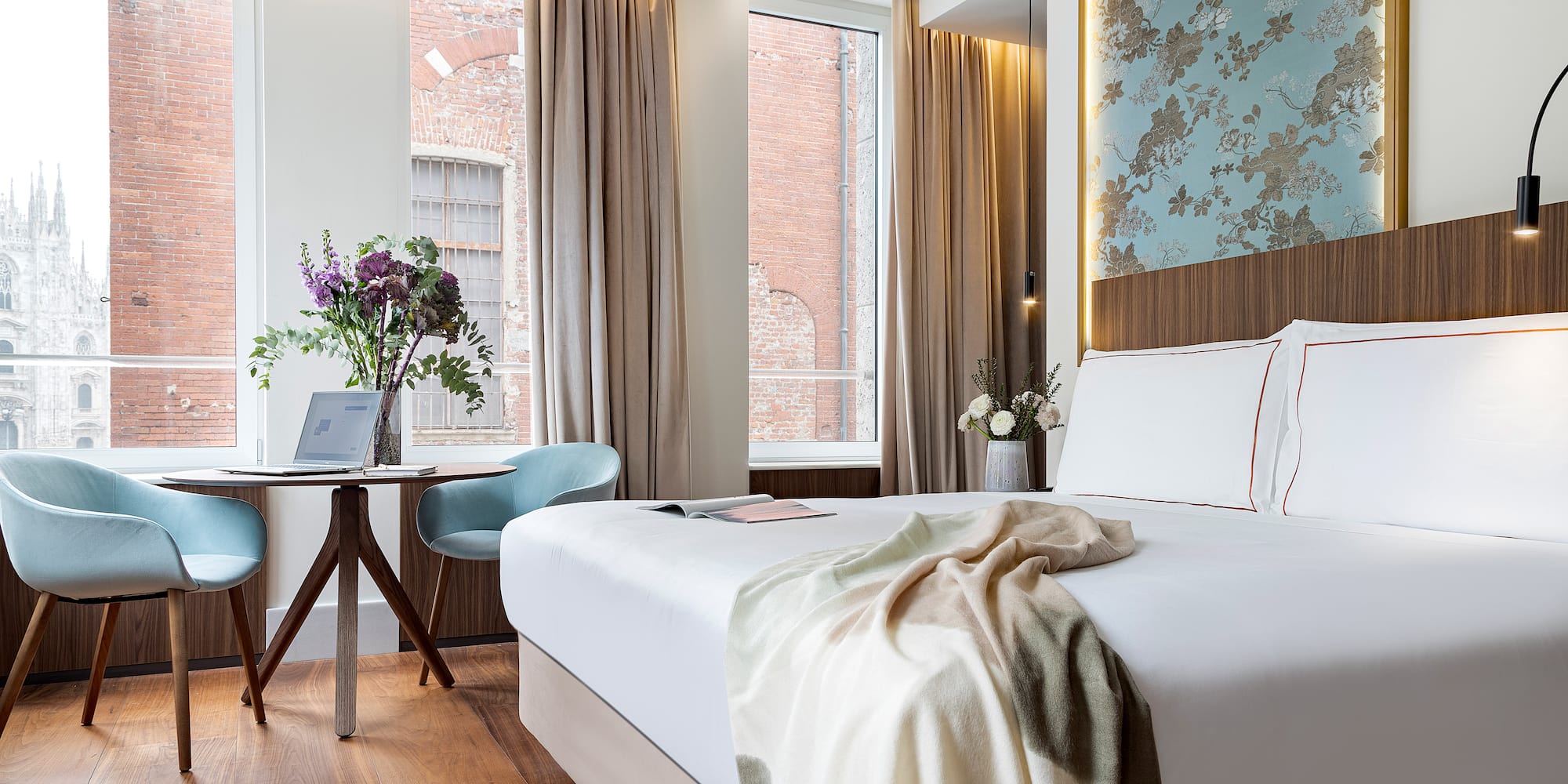 a bed with a blanket and a chair in a room with windows