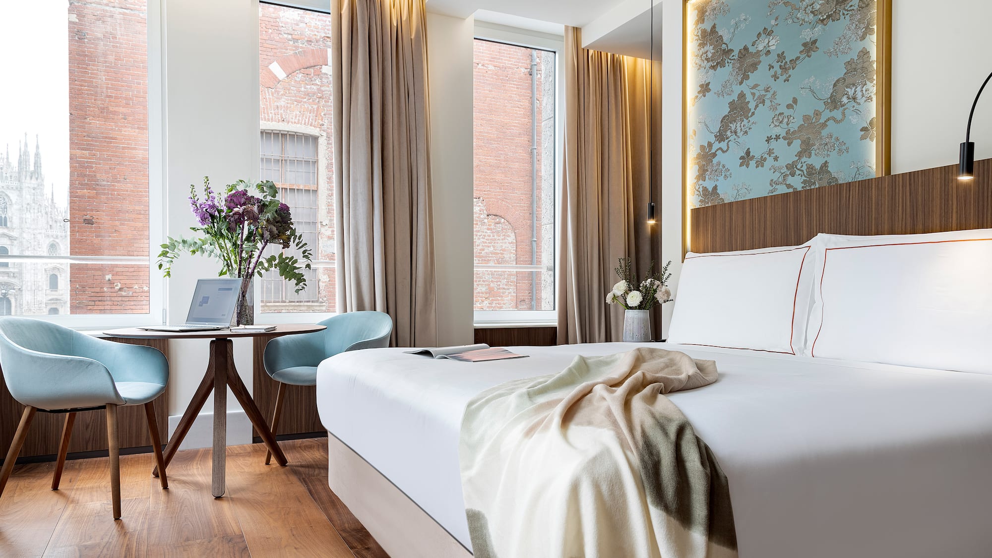 a bed with a blanket and a chair in a room with windows