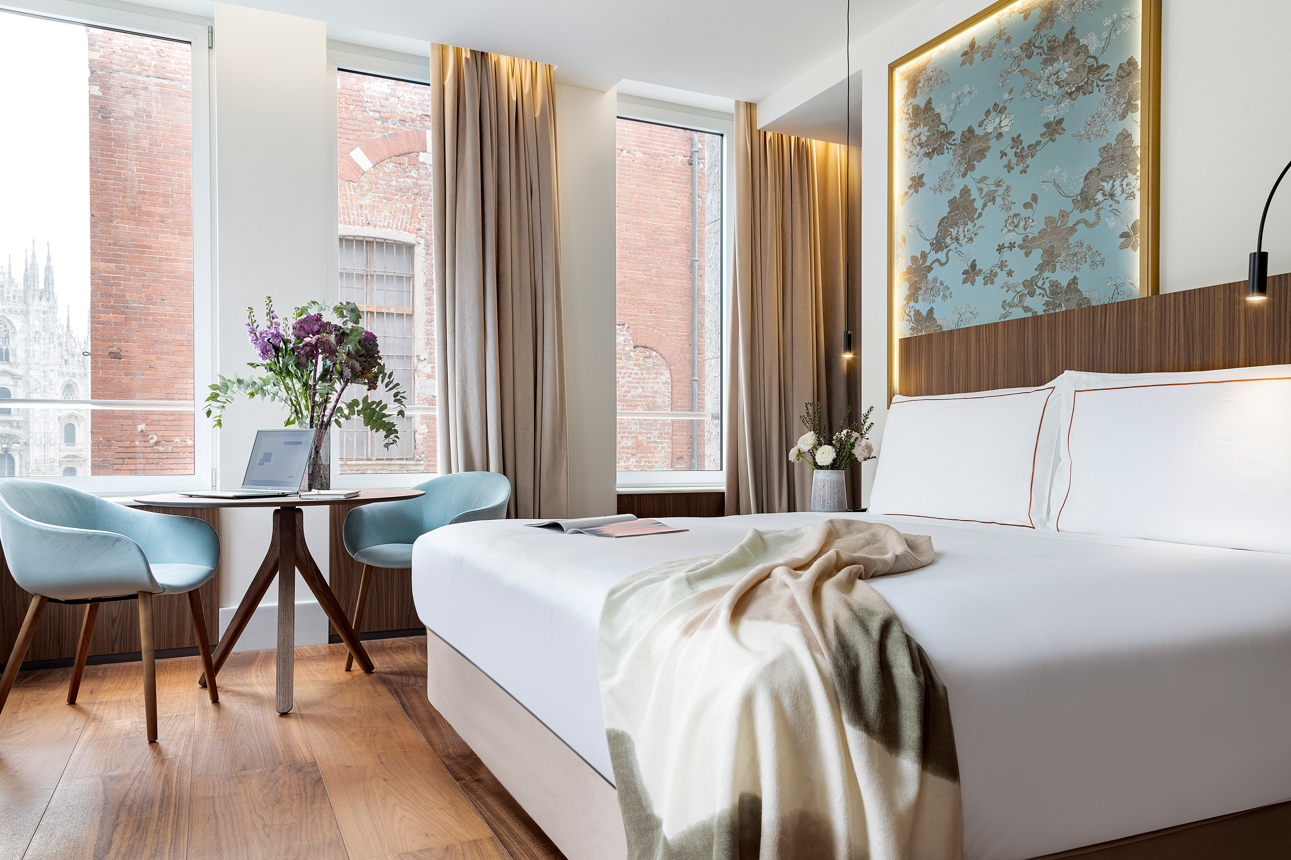 a bed with a blanket and a chair in a room with windows