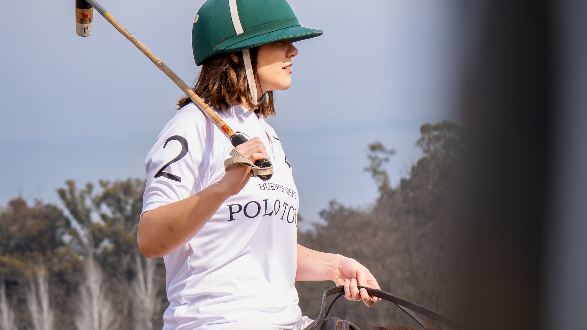 a woman wearing a helmet and holding a mallet on a horse