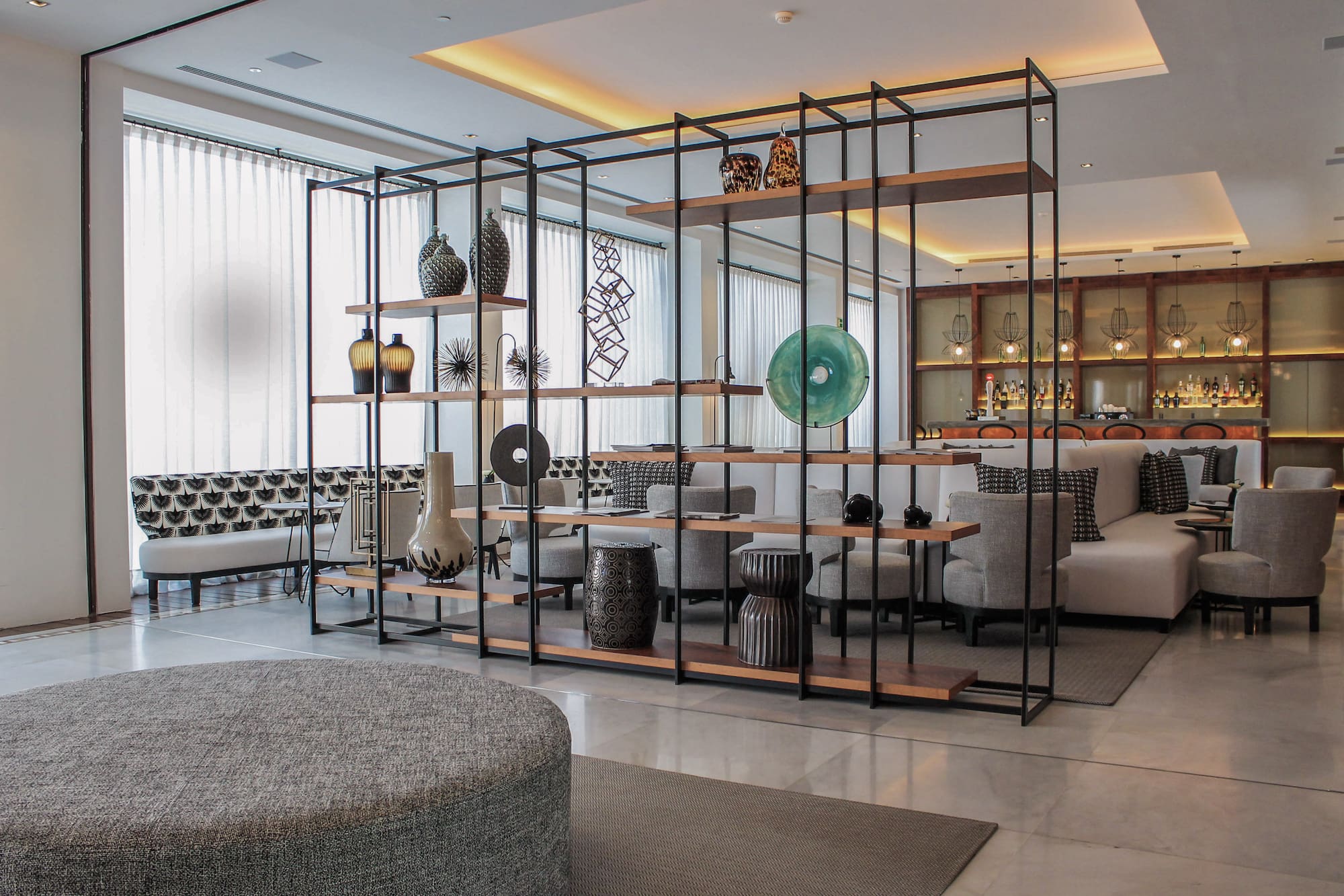 Modern hotel lounge interior with decorative room divider, stylish seating, and bar.