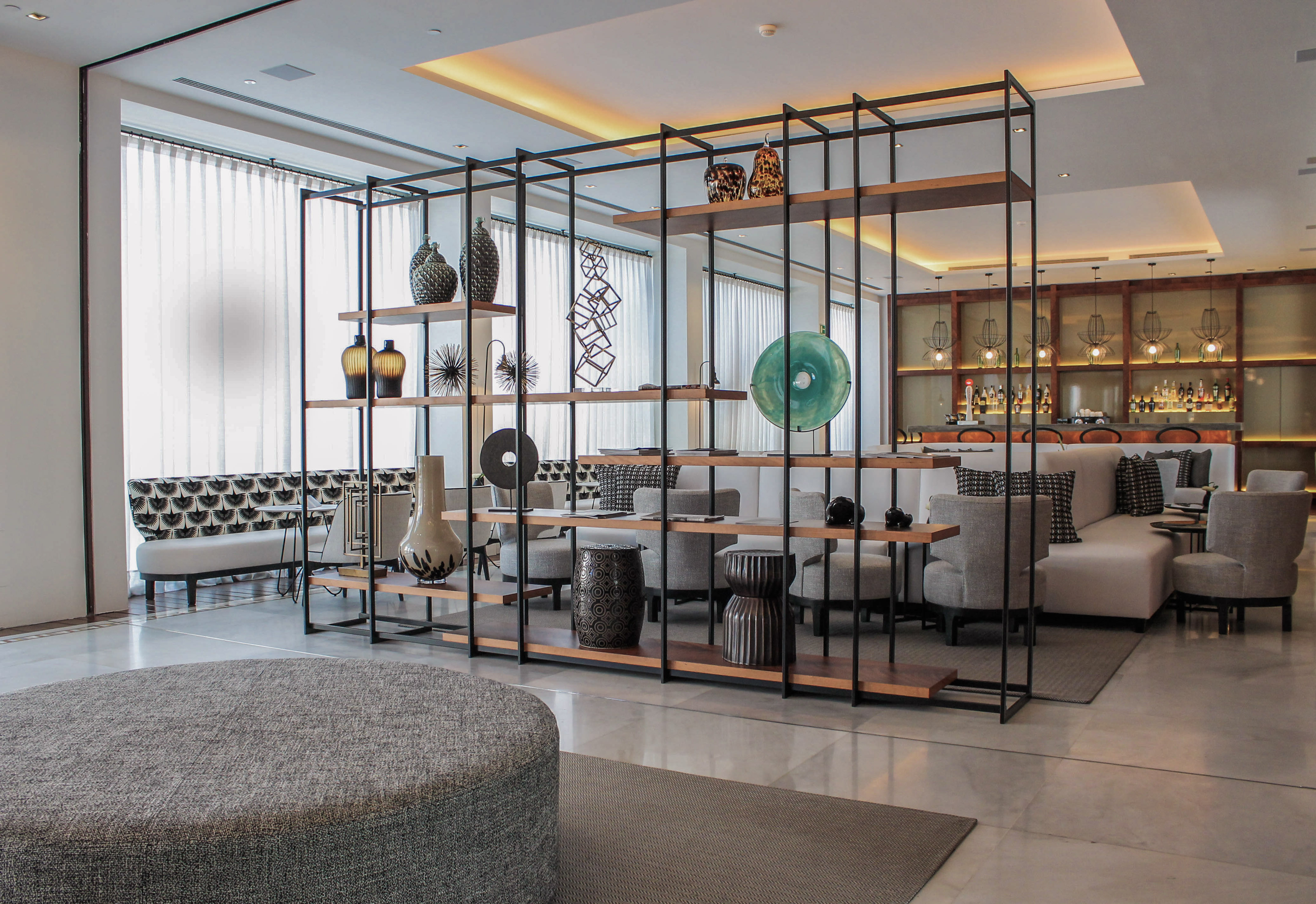 Modern hotel lounge interior with decorative room divider, stylish seating, and bar.