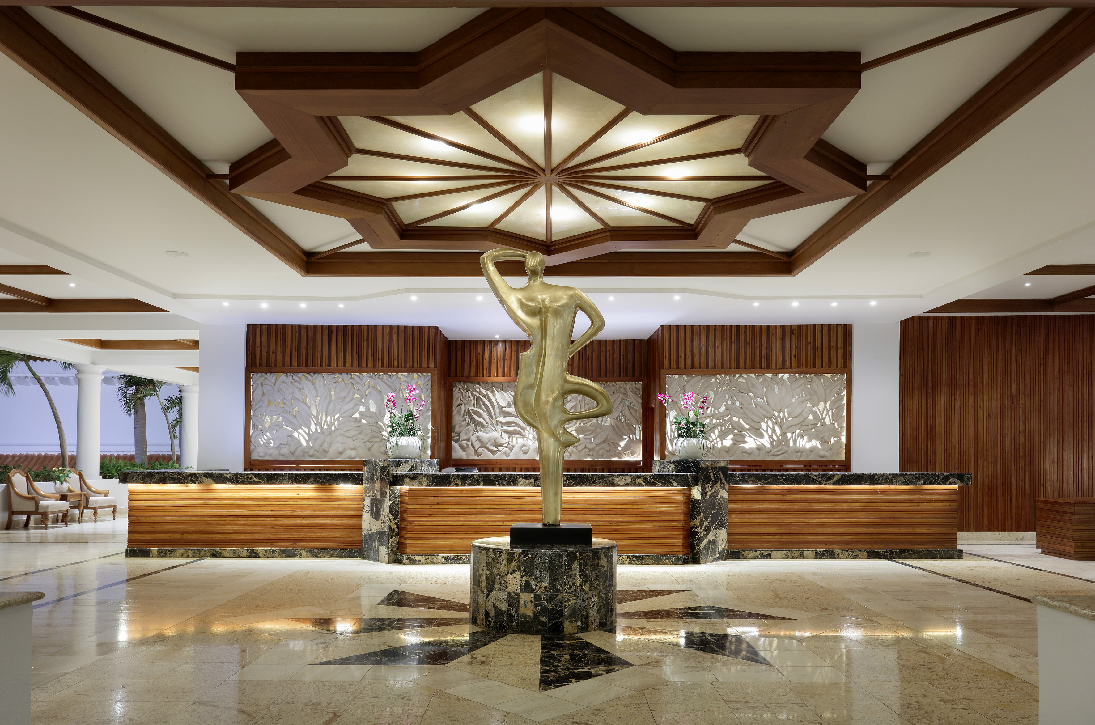 Golden sculpture in luxury hotel lobby with star ceiling and marble reception.
