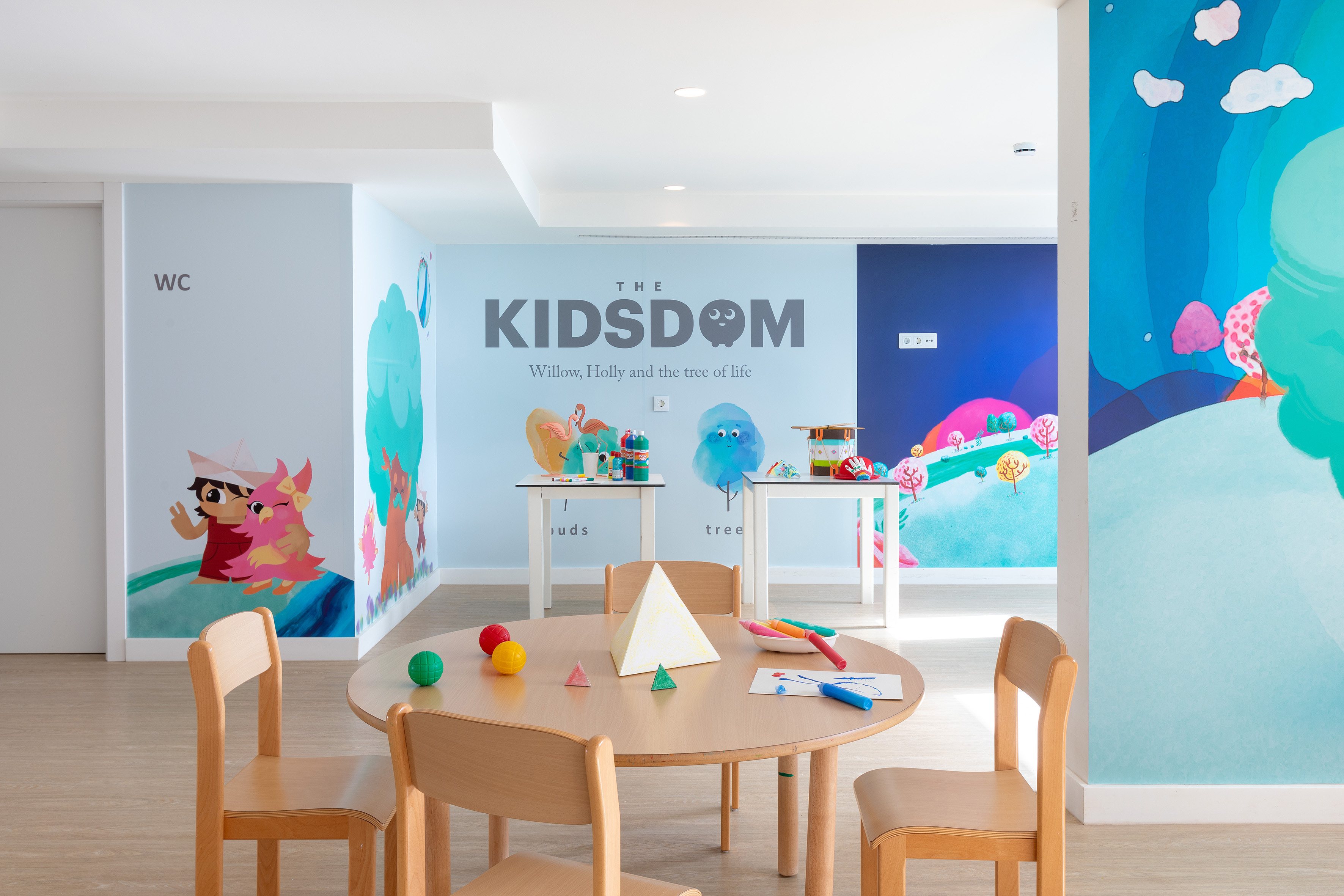 Colorful kids' play area with vibrant murals, small tables, and art supplies.