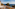 Hotel balcony with lounge chairs, refreshing drinks, fruit, and scenic ocean view.