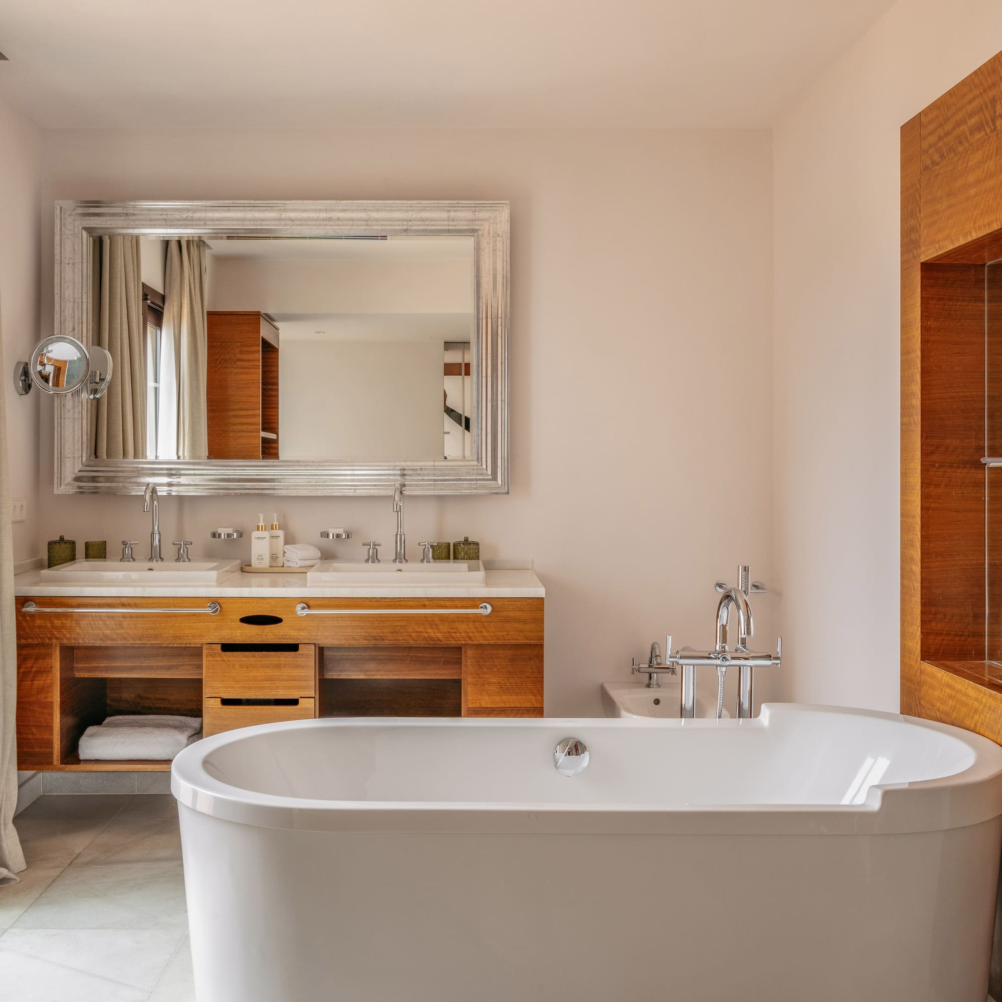 Luxury bathroom with freestanding tub, double vanity, and balcony with sea view.