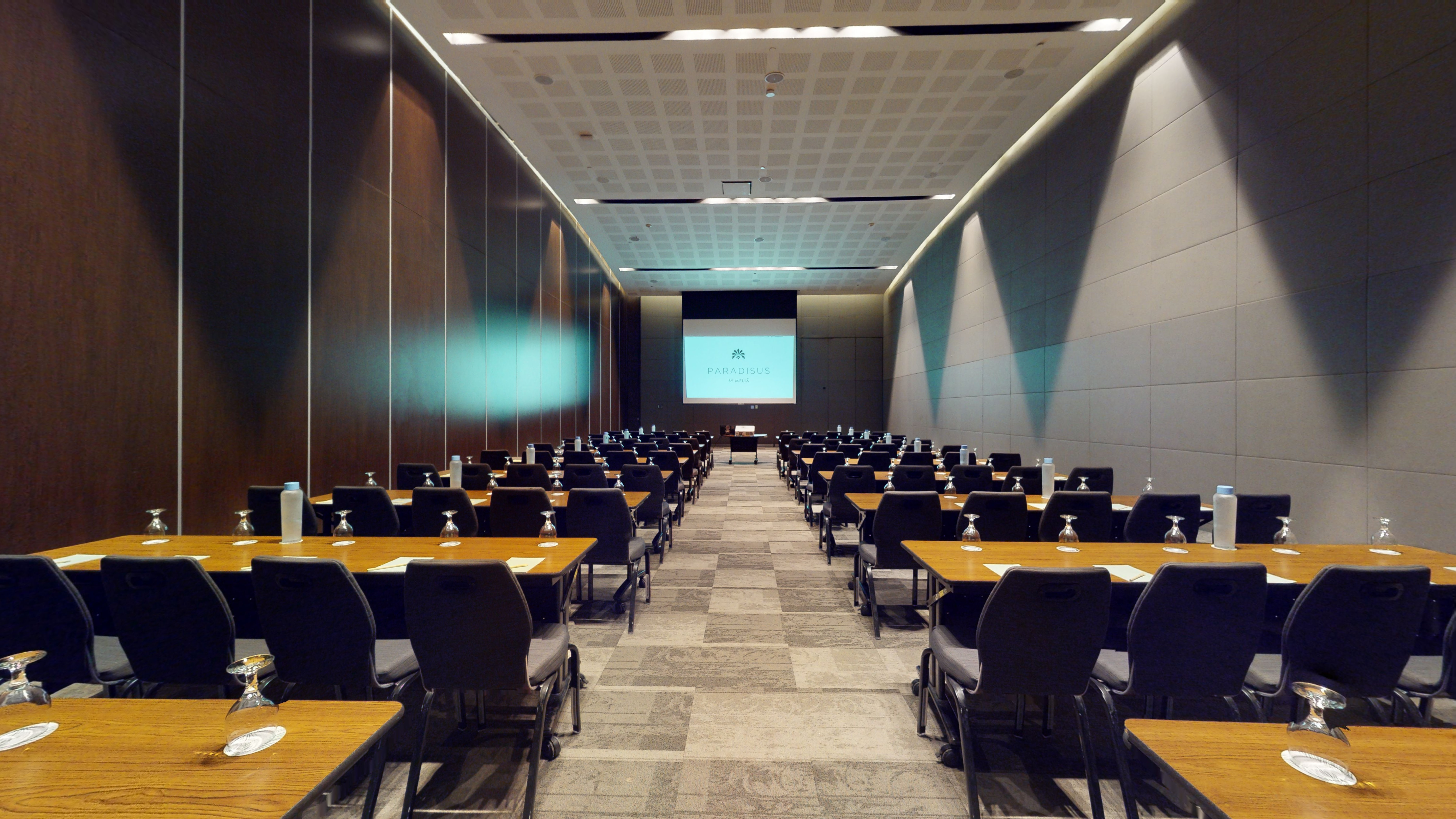 Modern hotel conference room setup with Paradisus screen, tables, and chairs.