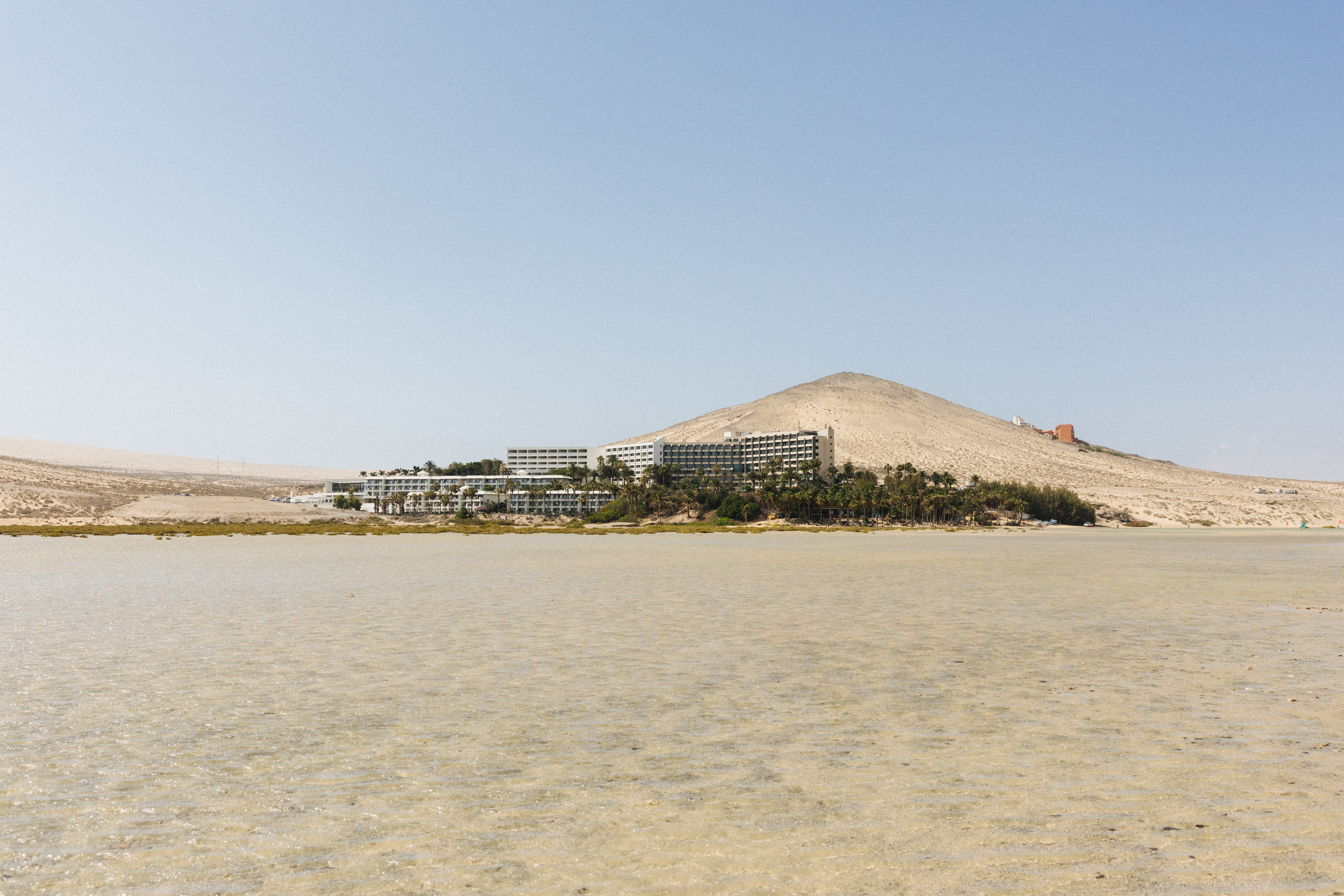 Beach resort, palm trees, sand dune, and shallow coastal lagoon.