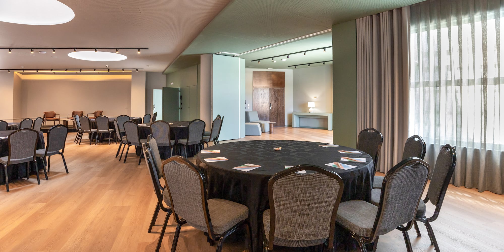 Modern conference room with round tables, chairs, and wooden flooring.