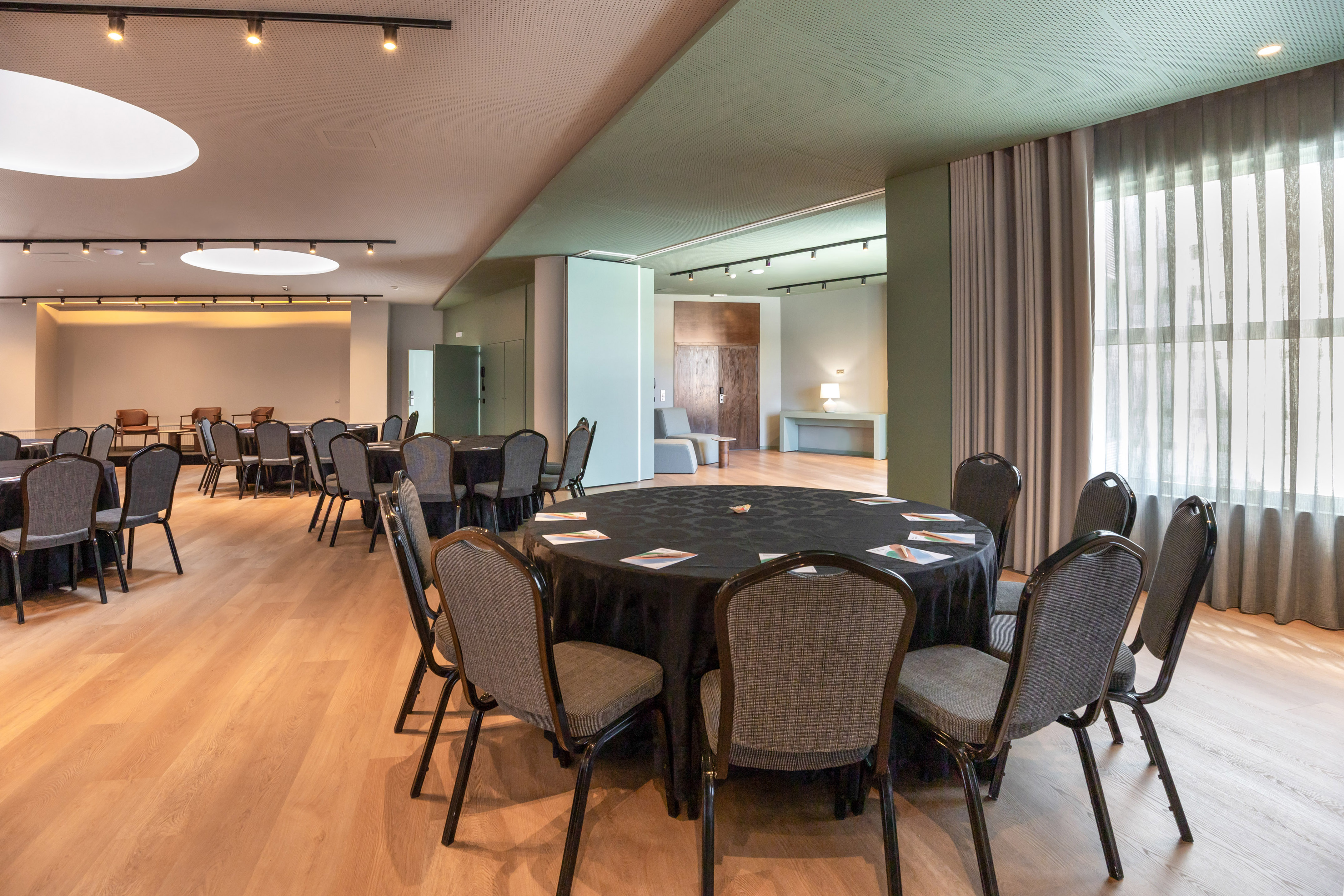 Modern conference room with round tables, chairs, and wooden flooring.