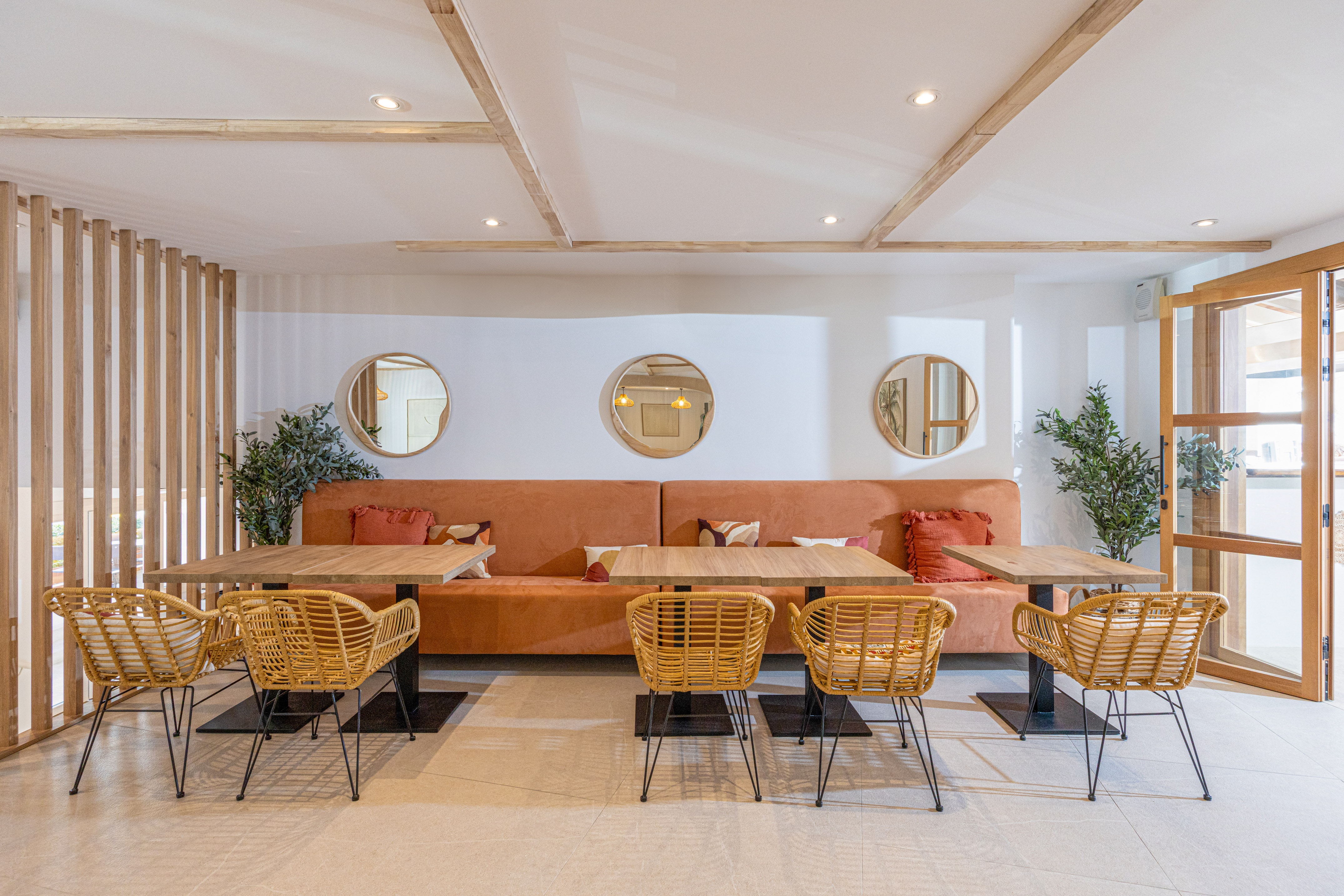 Stylish cafe lounge with orange upholstered booths, wood tables, rattan chairs.