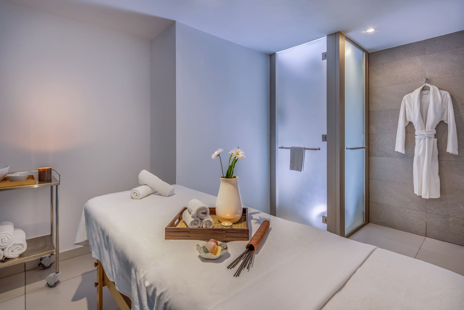 a massage table with towels and a vase of flowers