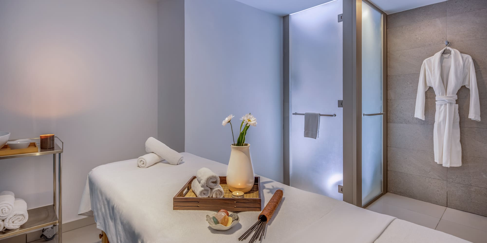 a massage table with towels and a vase of flowers