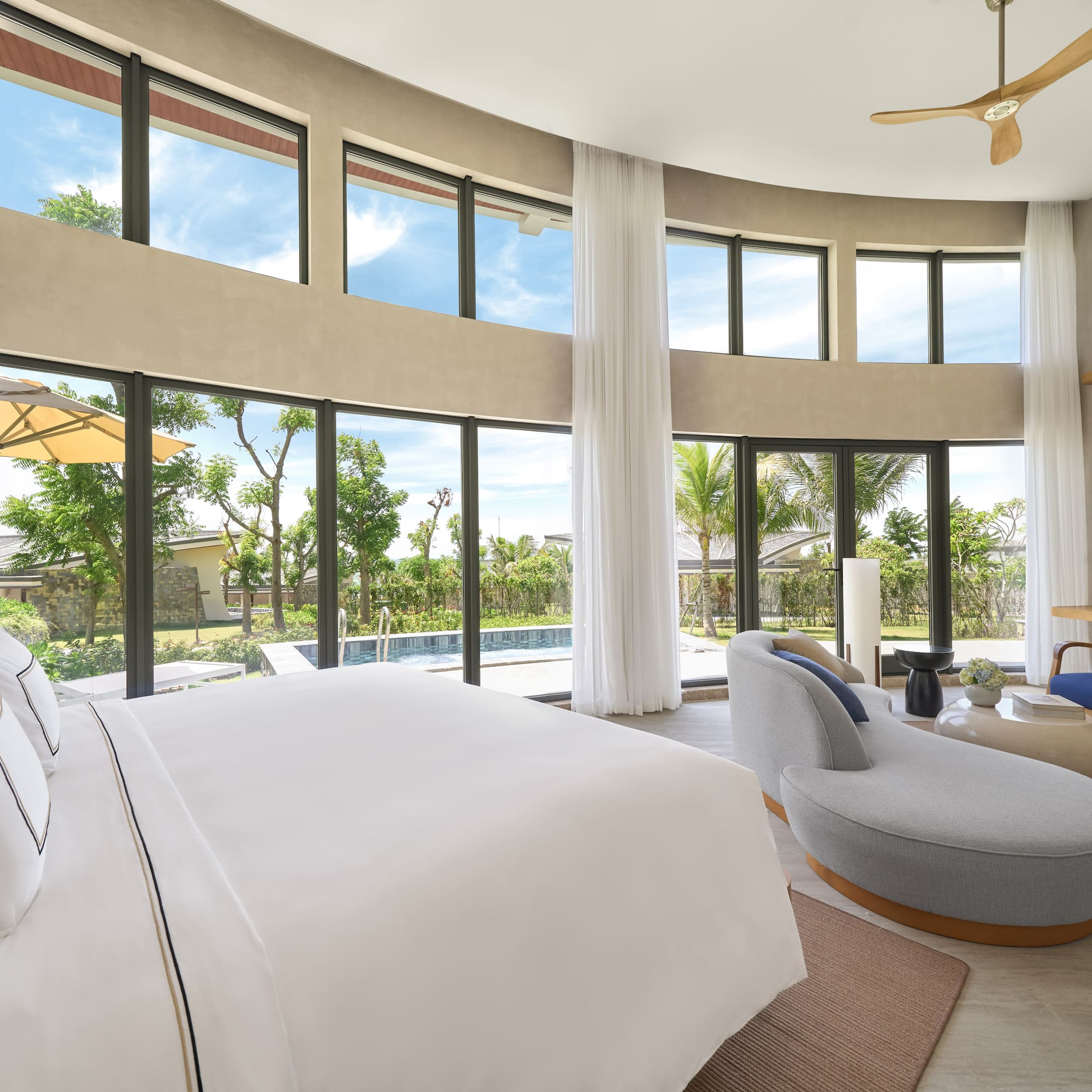 Luxury bedroom with pool view, expansive windows, and modern decor.