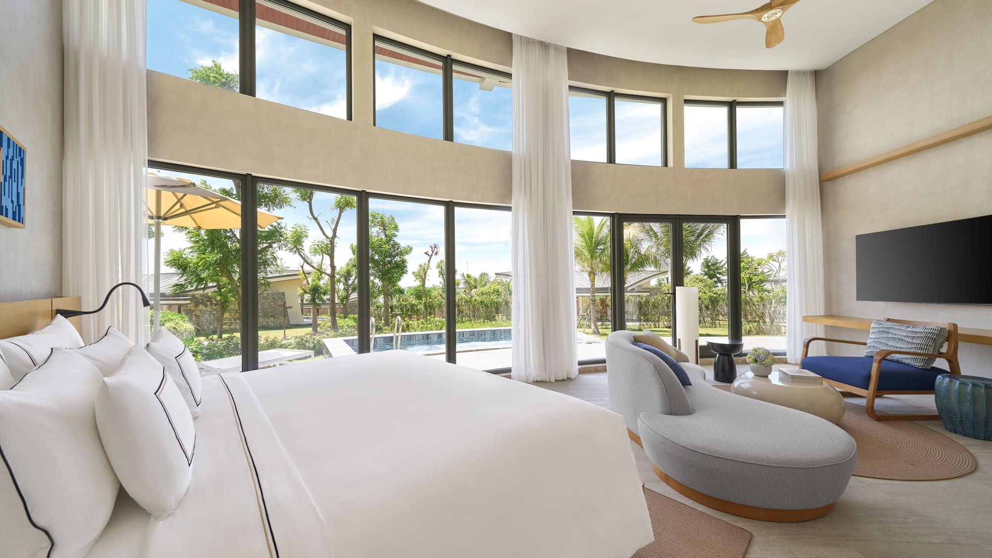 Luxury bedroom with pool view, expansive windows, and modern decor.