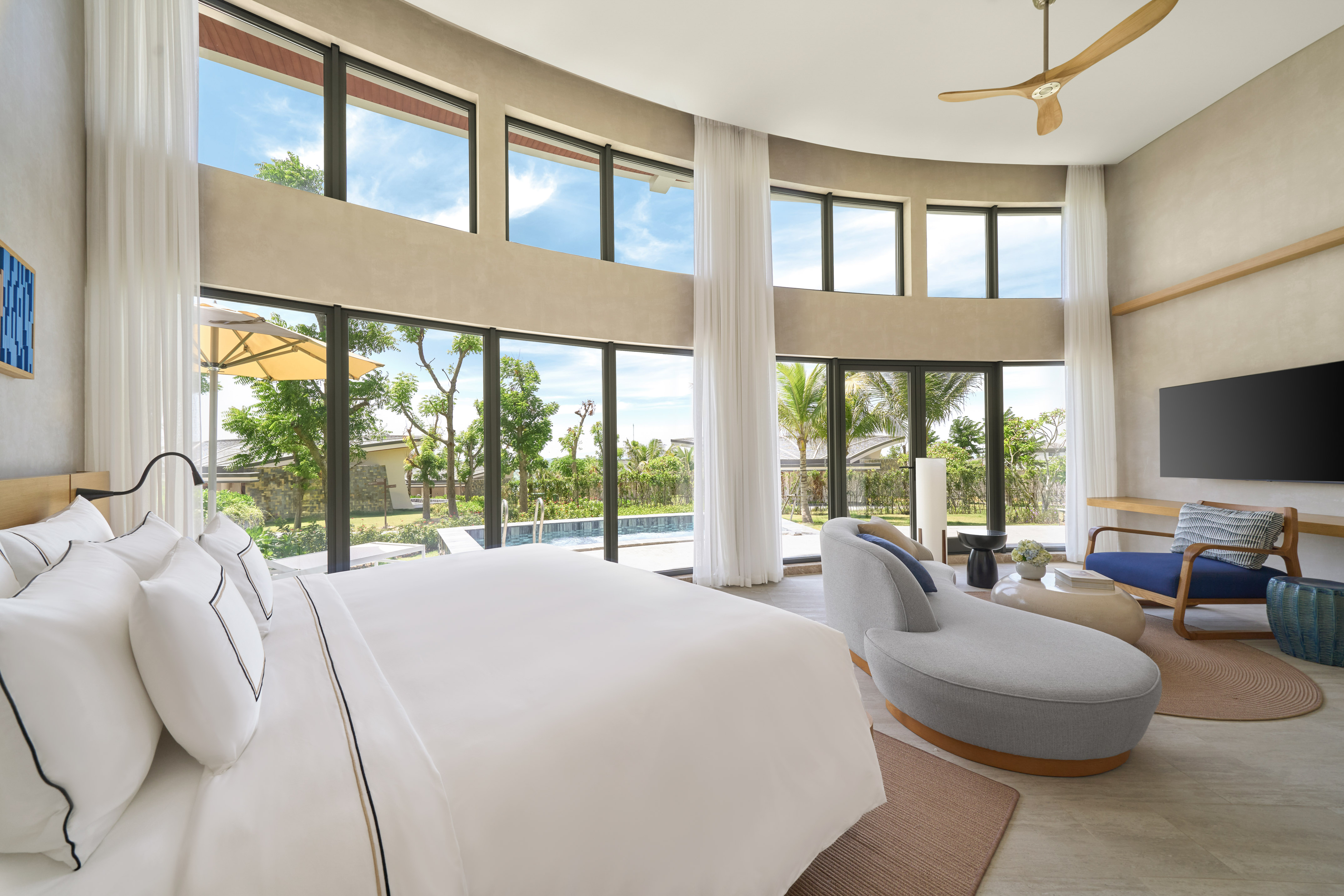 Luxury bedroom with pool view, expansive windows, and modern decor.