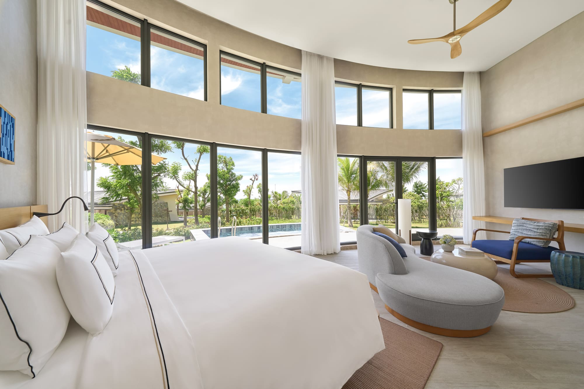 Luxury bedroom with pool view, expansive windows, and modern decor.