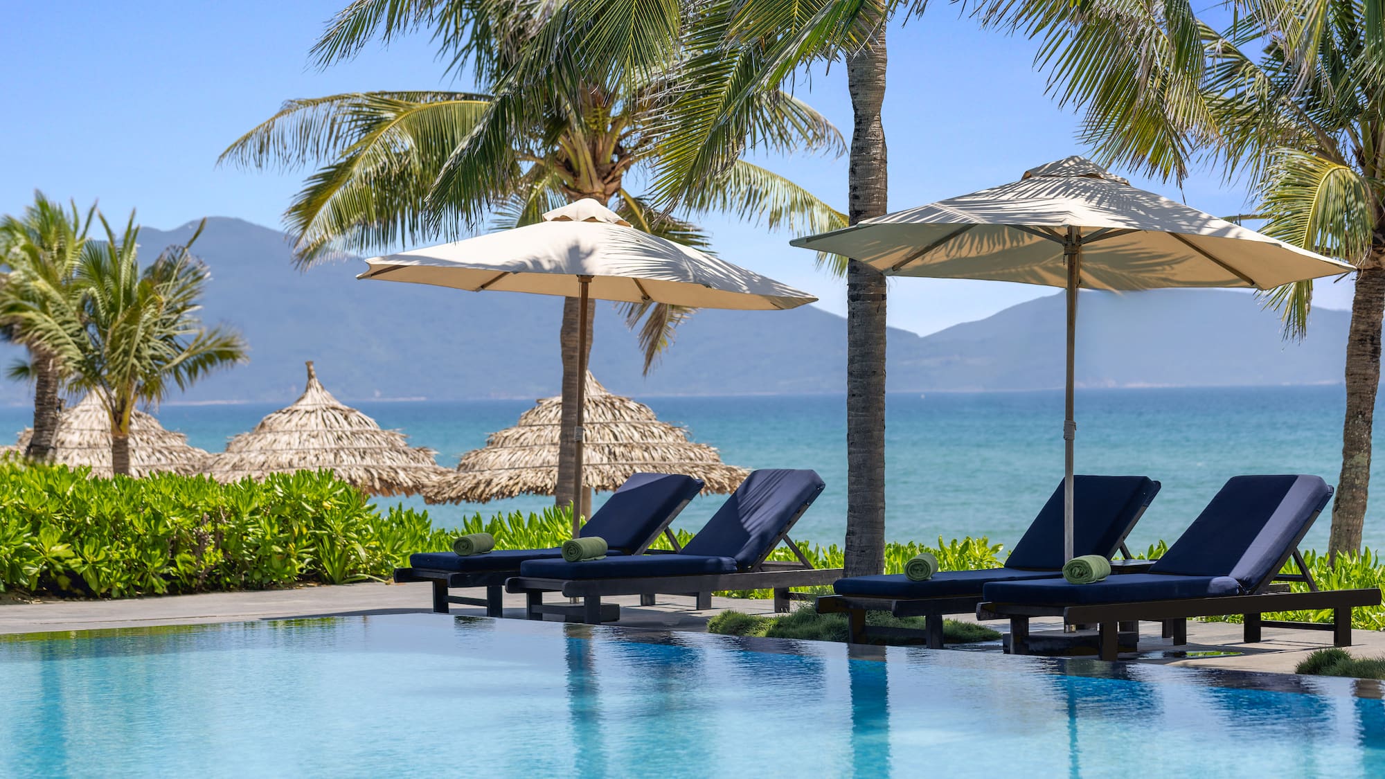 a pool with umbrellas and chairs by the water
