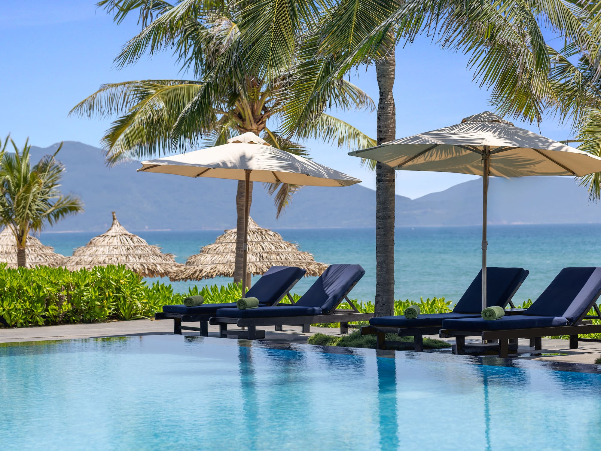 a pool with umbrellas and chairs by the water