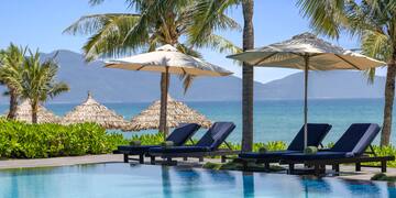 a pool with umbrellas and chairs by the water