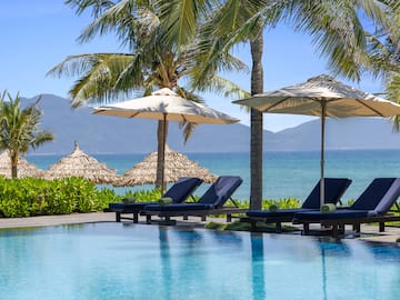a pool with umbrellas and chairs by the water