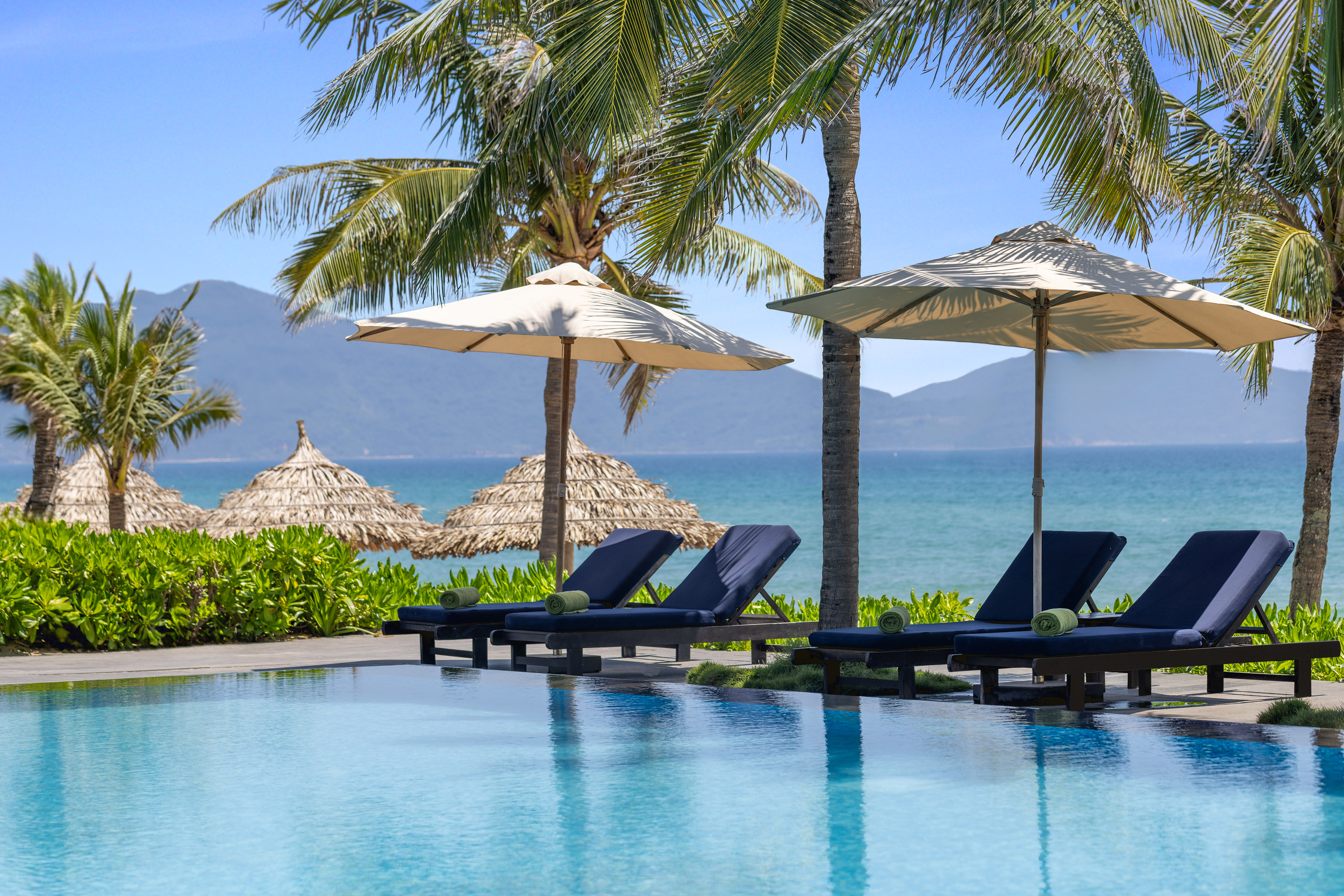 a pool with umbrellas and chairs by the water