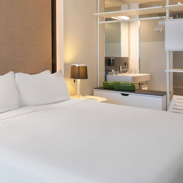 a bed with white sheets and a sink in a room