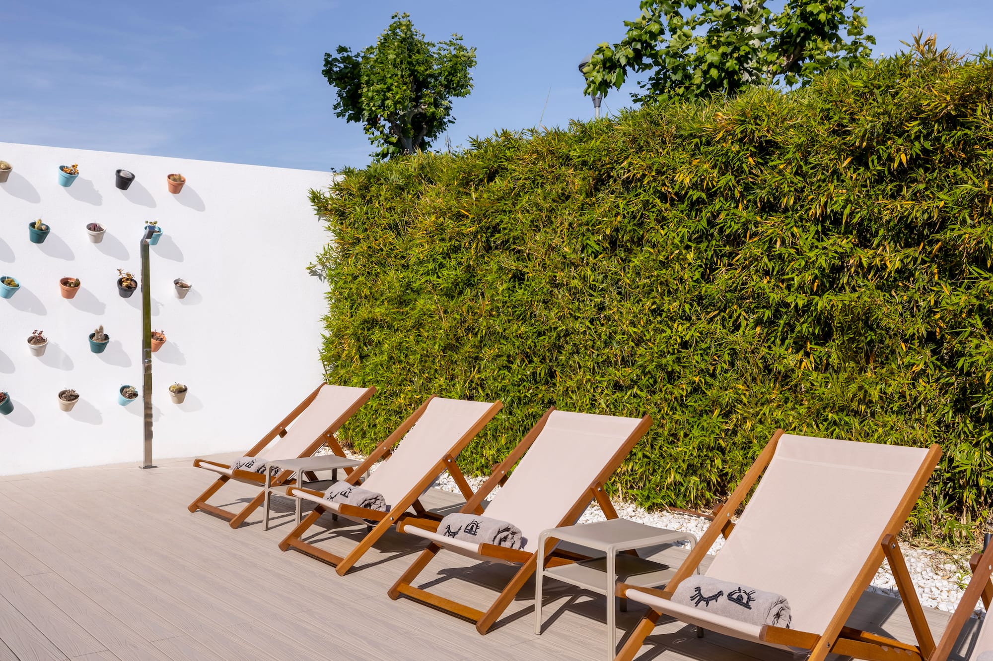 Outdoor lounge with four deck chairs, bamboo hedge, and succulent wall.