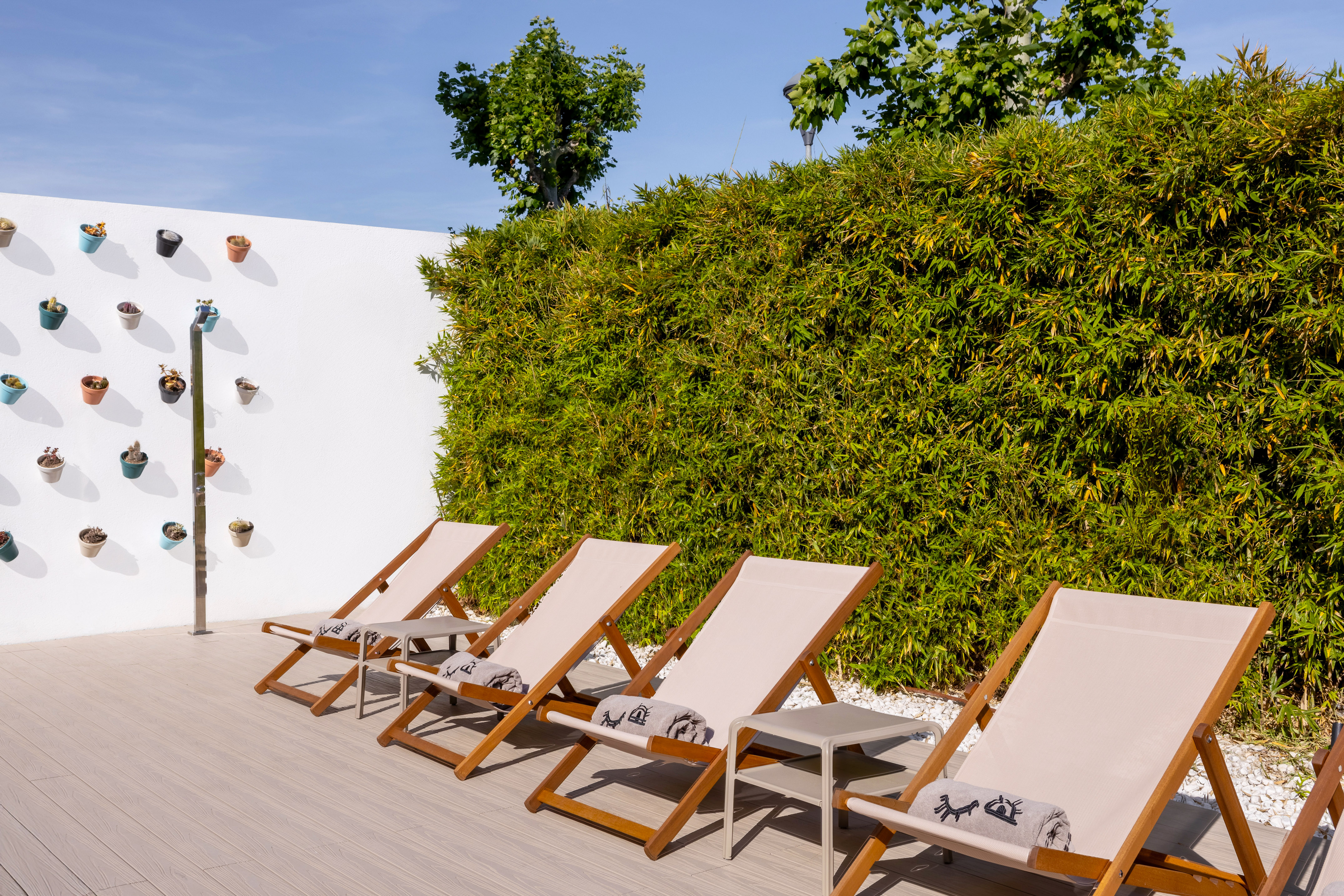 Outdoor lounge with four deck chairs, bamboo hedge, and succulent wall.